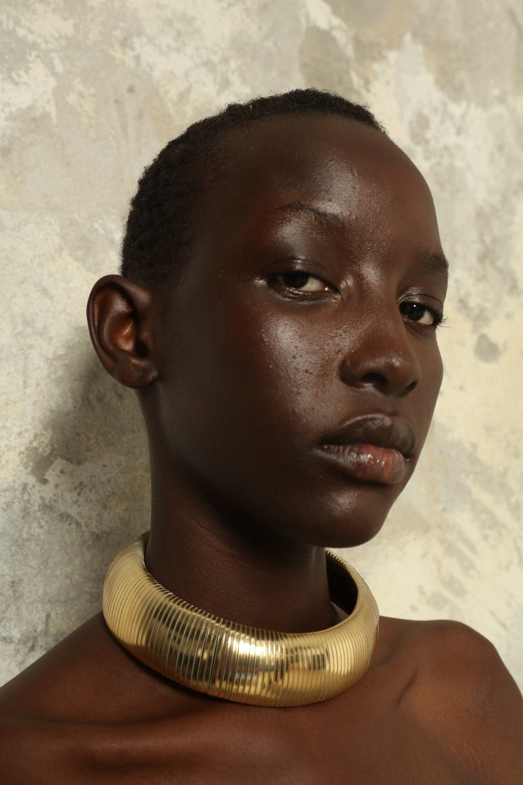 Model is wearing Halo Gold Foil Leather Necklace by SO-LE STUDIO, handcrafted from upcycled Italian leather in a bold circular form with gold foil finish, part of the curated selection at House of Woven Stories, combining lightweight comfort with sculptural presence and conscious Italian craftsmanship.