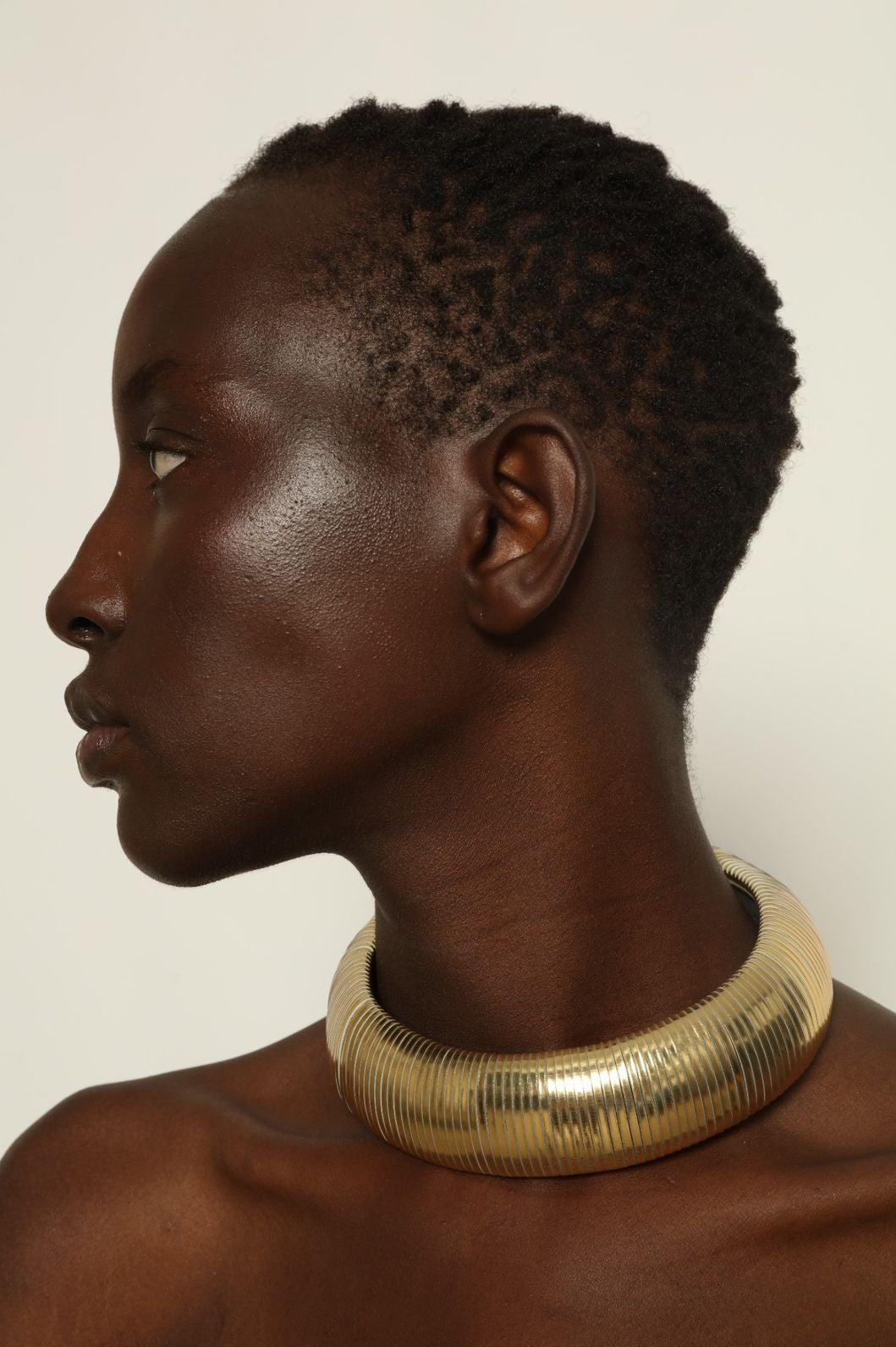 Model is wearing Halo Gold Foil Leather Necklace by SO-LE STUDIO, handcrafted from upcycled Italian leather in a bold circular form with gold foil finish, part of the curated selection at House of Woven Stories, combining lightweight comfort with sculptural presence and conscious Italian craftsmanship.