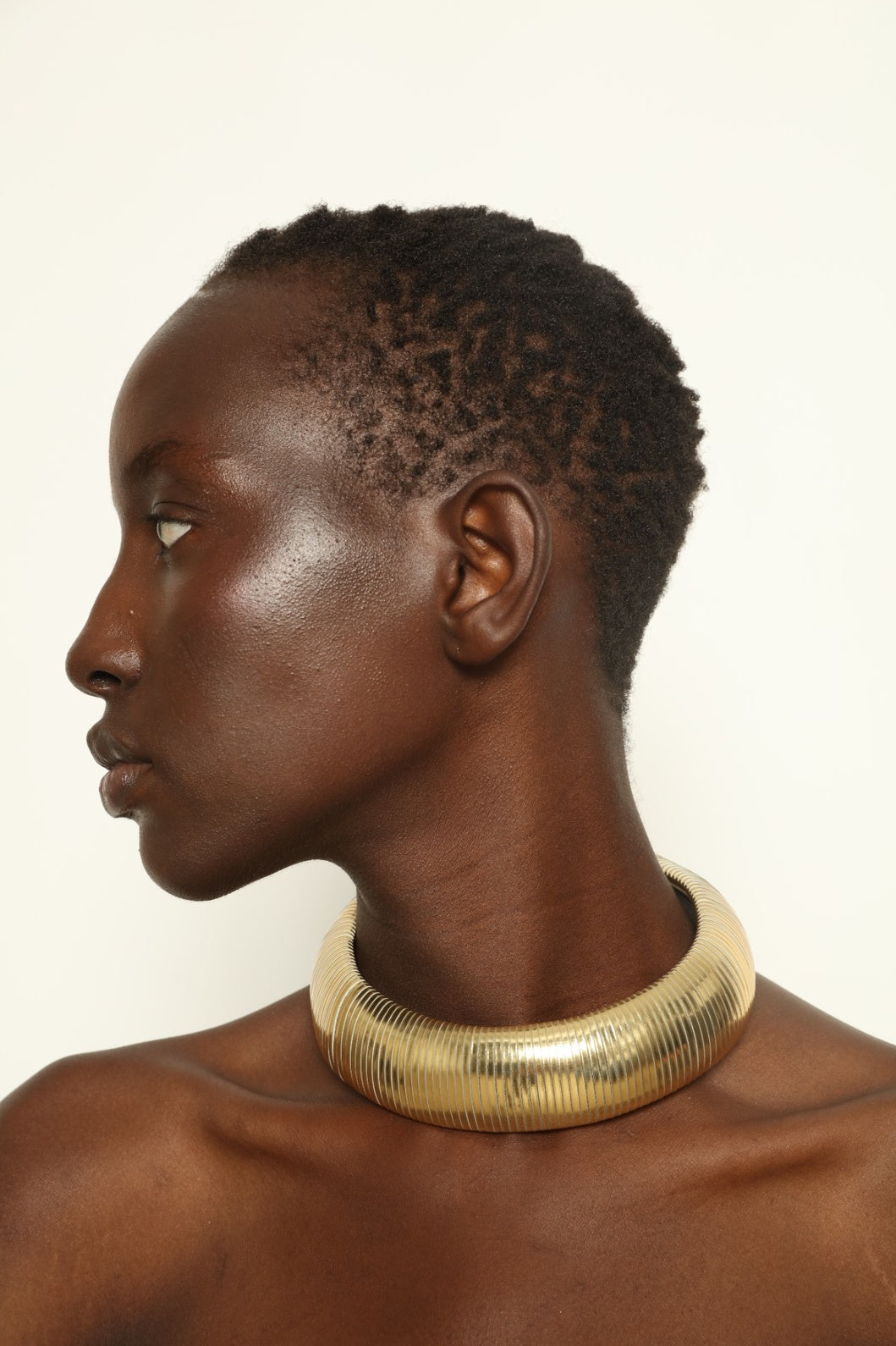 Model is wearing Halo Gold Foil Leather Necklace by SO-LE STUDIO, handcrafted from upcycled Italian leather in a bold circular form with gold foil finish, part of the curated selection at House of Woven Stories, combining lightweight comfort with sculptural presence and conscious Italian craftsmanship.