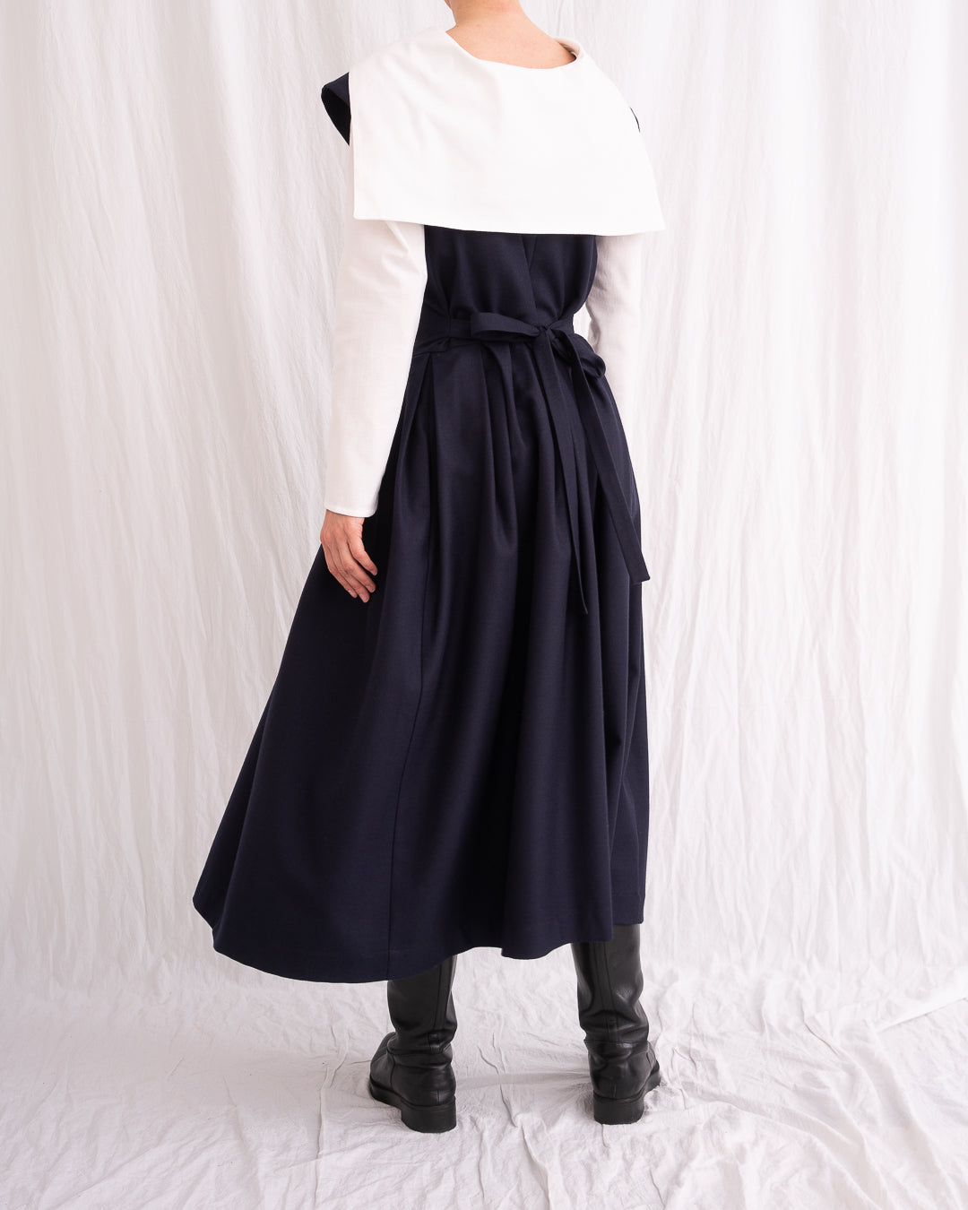 Model is wearing the Sarafan Pure New Wool Dress by Les Vacances d’Irina, a handmade navy merino wool dress with A-line silhouette, tie-back detail, horn buttons, and side pockets, available at House of Woven Stories.