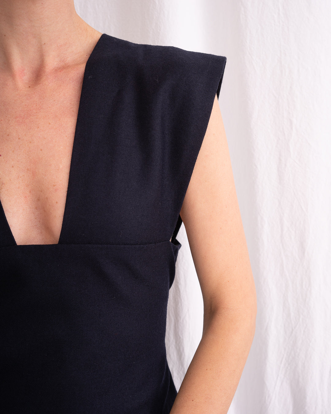 Model is wearing the Sarafan Pure New Wool Dress by Les Vacances d’Irina, a handmade navy merino wool dress with A-line silhouette, tie-back detail, horn buttons, and side pockets, available at House of Woven Stories.