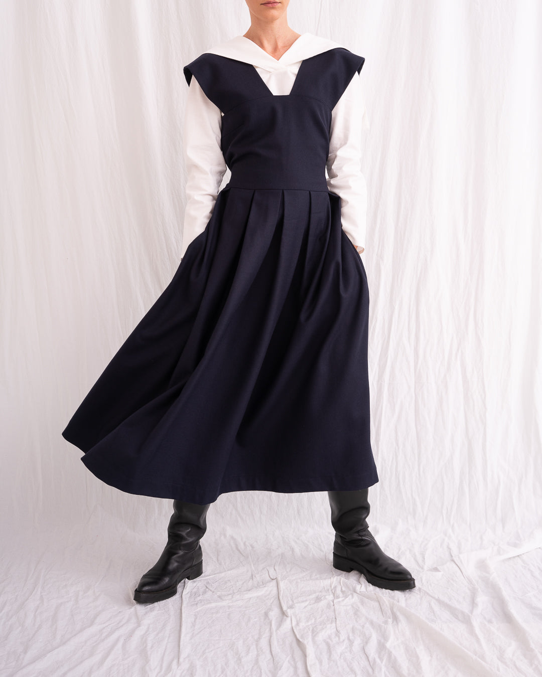 Model is wearing the Sarafan Pure New Wool Dress by Les Vacances d’Irina, a handmade navy merino wool dress with A-line silhouette, tie-back detail, horn buttons, and side pockets, available at House of Woven Stories.
