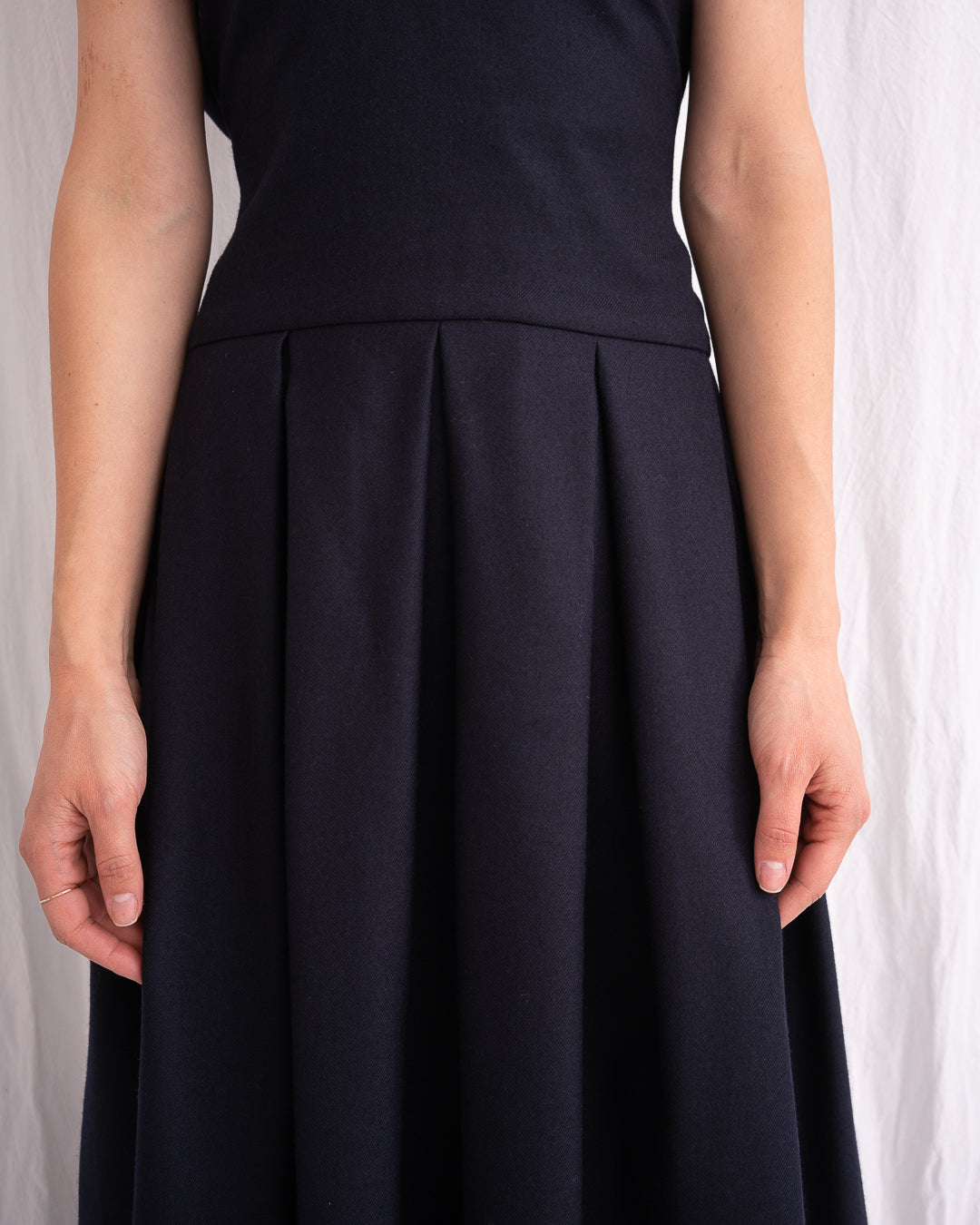 Model is wearing the Sarafan Pure New Wool Dress by Les Vacances d’Irina, a handmade navy merino wool dress with A-line silhouette, tie-back detail, horn buttons, and side pockets, available at House of Woven Stories.