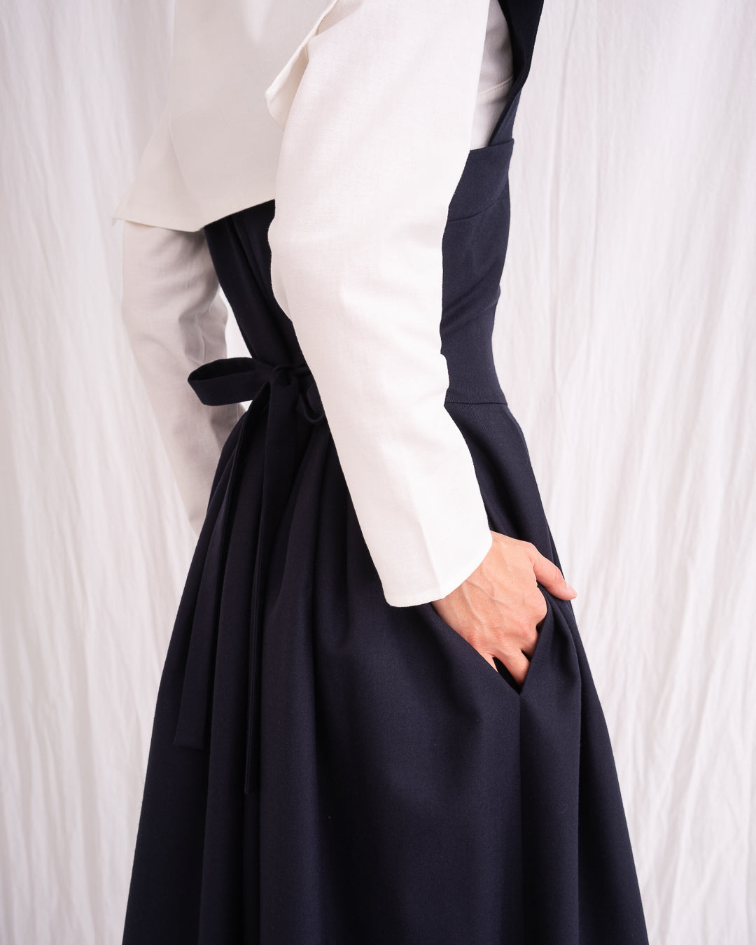 Model is wearing the Sarafan Pure New Wool Dress by Les Vacances d’Irina, a handmade navy merino wool dress with A-line silhouette, tie-back detail, horn buttons, and side pockets, available at House of Woven Stories.