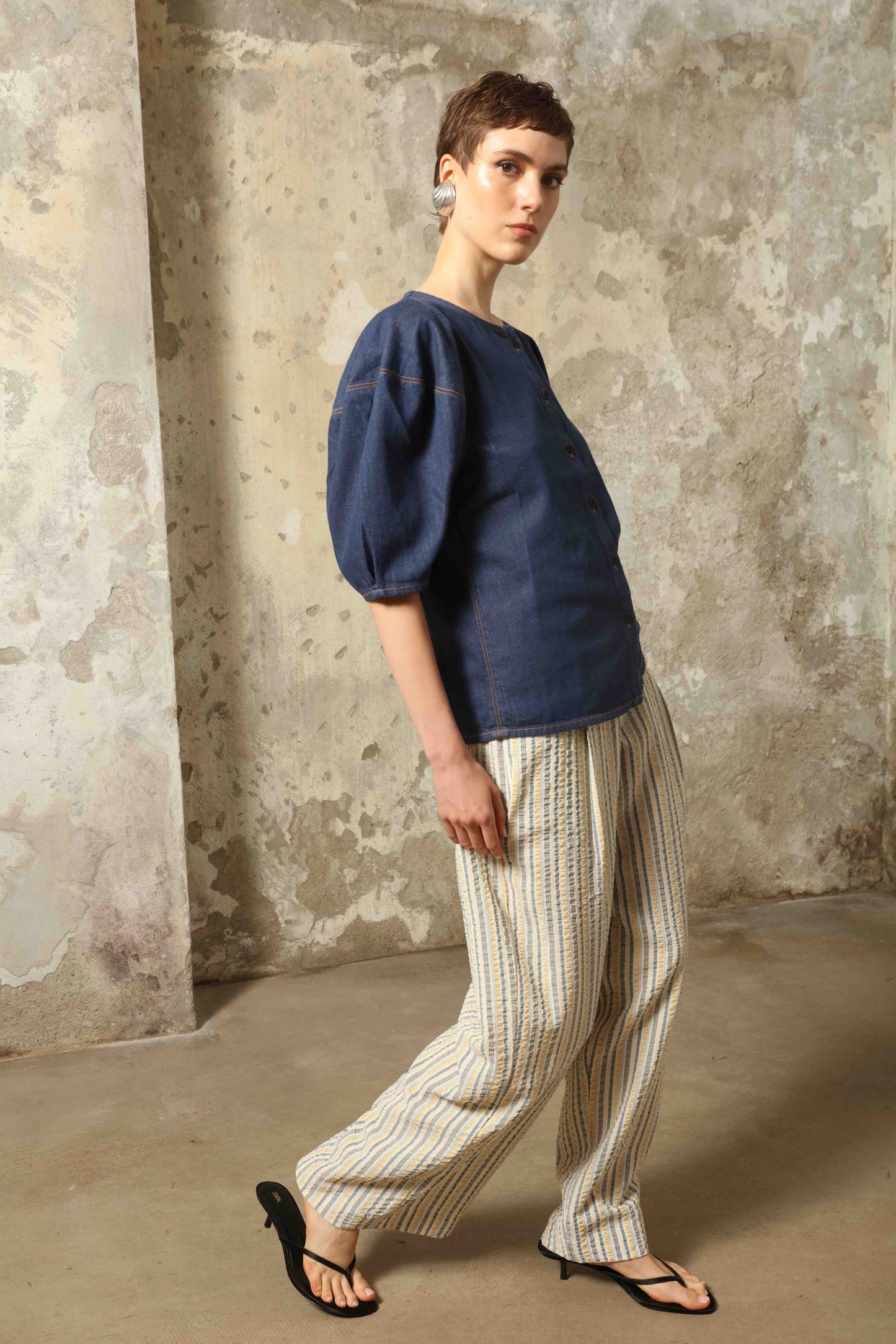 Model wearing the Blouse Bubble Brut in cotton denim by Happy Haus, featuring balloon sleeves, straight-cut silhouette, round neckline, and tobacco topstitching in a lightweight, breathable fabric.