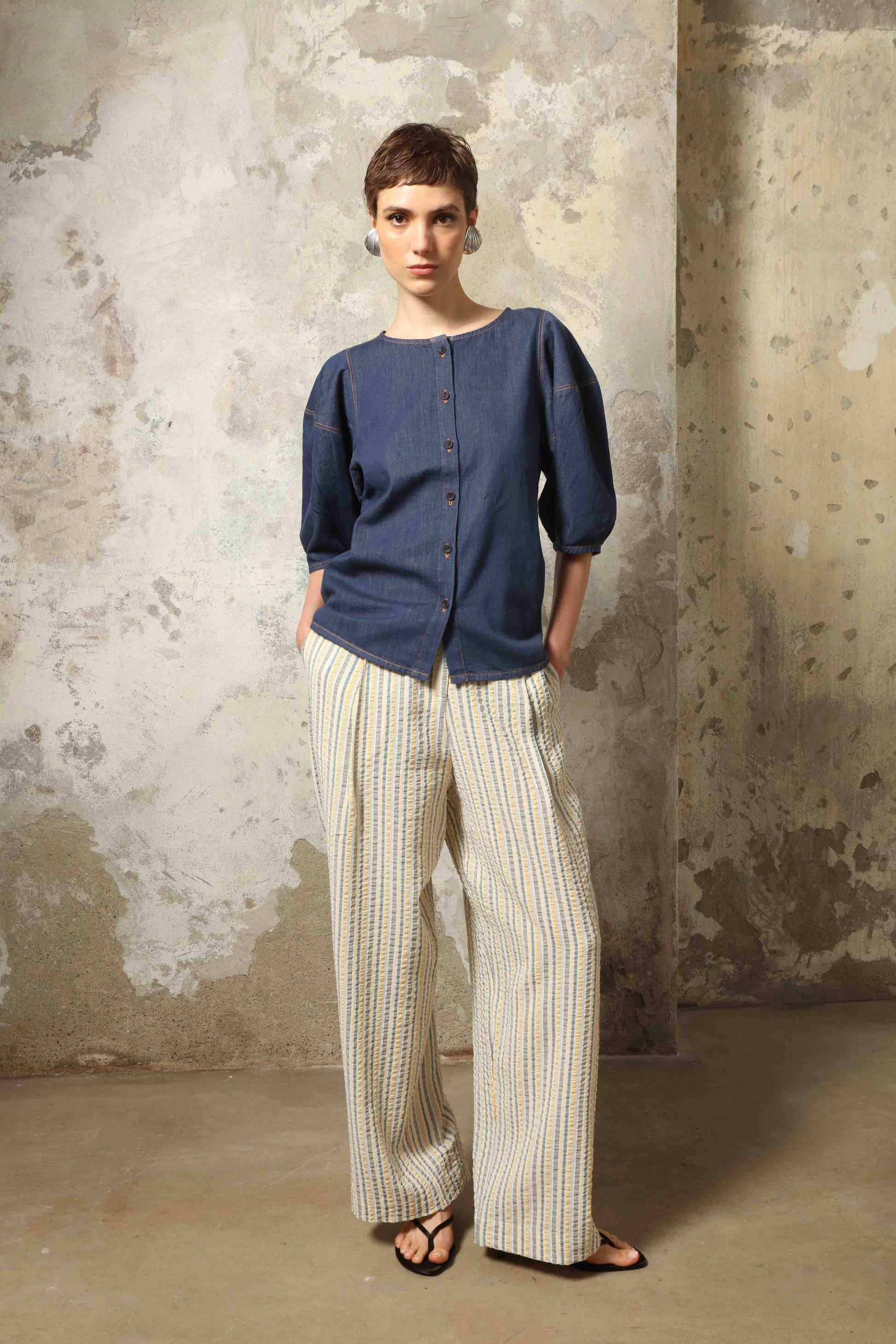 Model wearing the Blouse Bubble Brut in cotton denim by Happy Haus, featuring balloon sleeves, straight-cut silhouette, round neckline, and tobacco topstitching in a lightweight, breathable fabric.