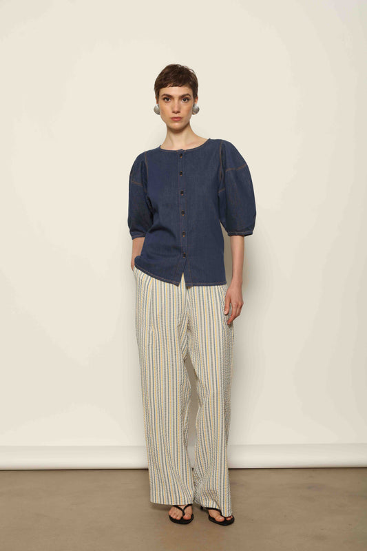 Model wearing the Blouse Bubble Brut in cotton denim by Happy Haus, featuring balloon sleeves, straight-cut silhouette, round neckline, and tobacco topstitching in a lightweight, breathable fabric.