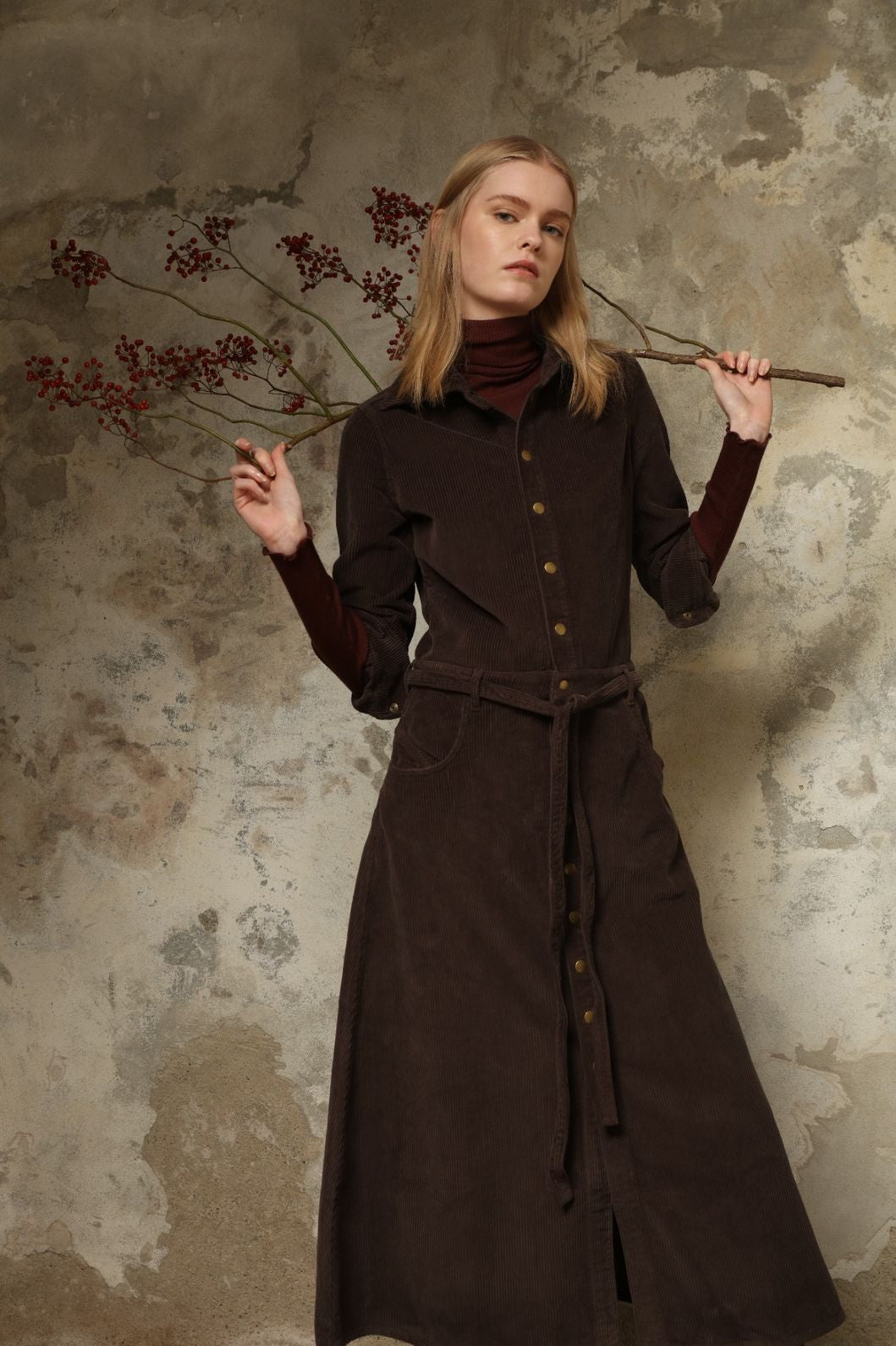 Model is wearing La Robe Trompe L’Oeil in Chocolate by Happy Haus, a corduroy cotton trompe-l’œil dress with removable belt, tulip-shaped pockets and brass snaps, curated in the House of Woven Stories selection.