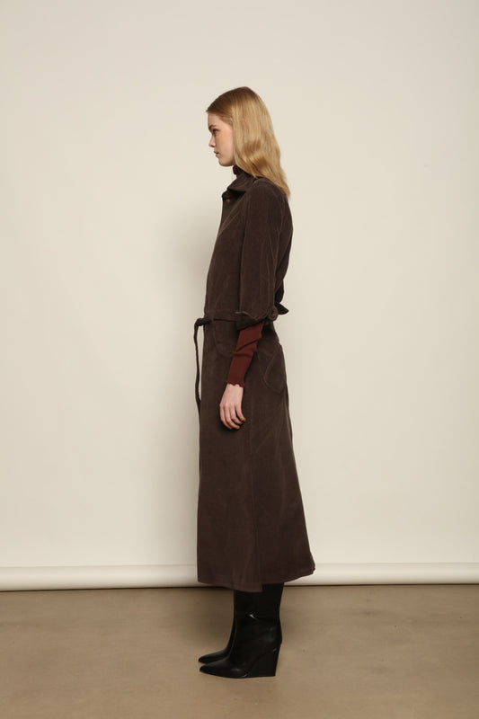 Model is wearing La Robe Trompe L’Oeil in Chocolate by Happy Haus, a corduroy cotton trompe-l’œil dress with removable belt, tulip-shaped pockets and brass snaps, curated in the House of Woven Stories selection.