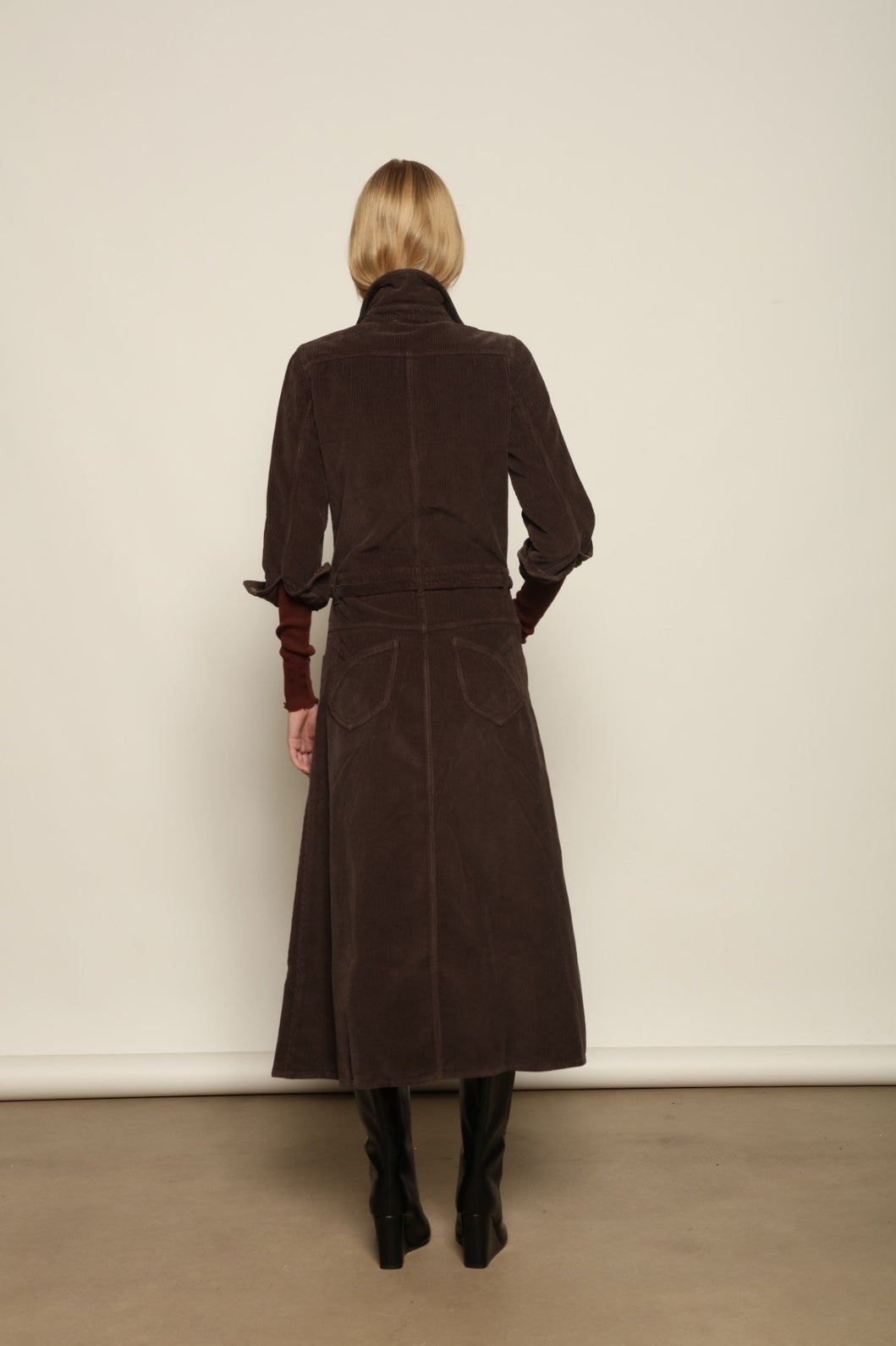 Model is wearing La Robe Trompe L’Oeil in Chocolate by Happy Haus, a corduroy cotton trompe-l’œil dress with removable belt, tulip-shaped pockets and brass snaps, curated in the House of Woven Stories selection.