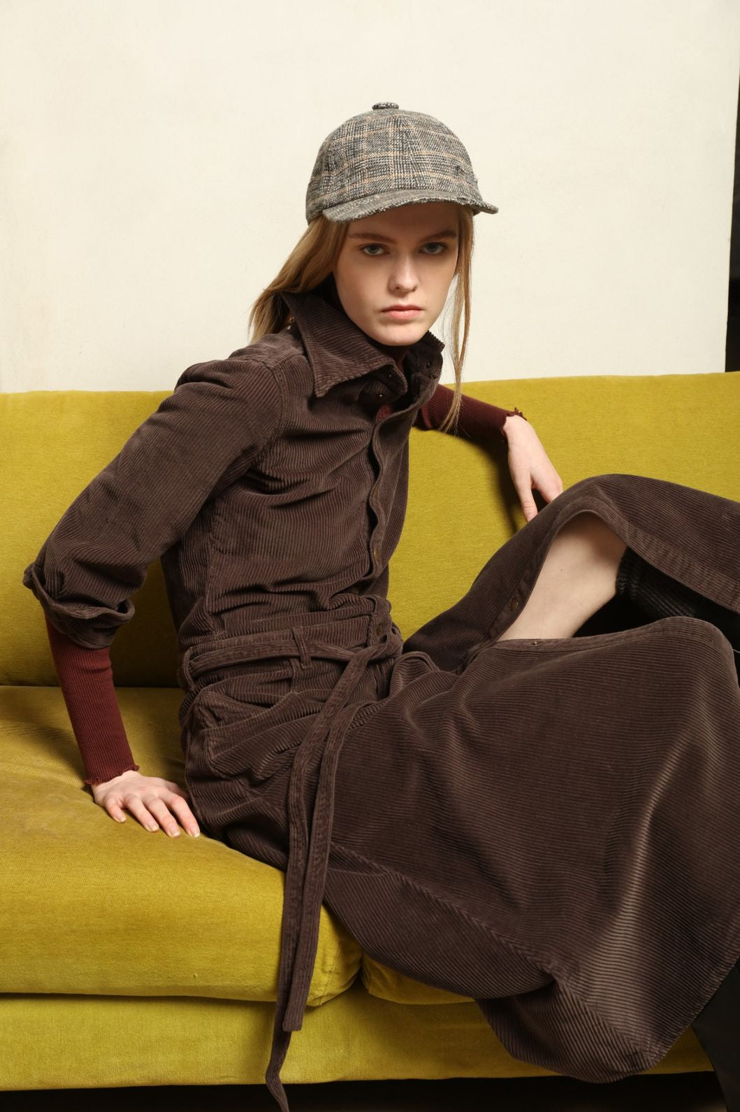 Model is wearing La Robe Trompe L’Oeil in Chocolate by Happy Haus, a corduroy cotton trompe-l’œil dress with removable belt, tulip-shaped pockets and brass snaps, curated in the House of Woven Stories selection.