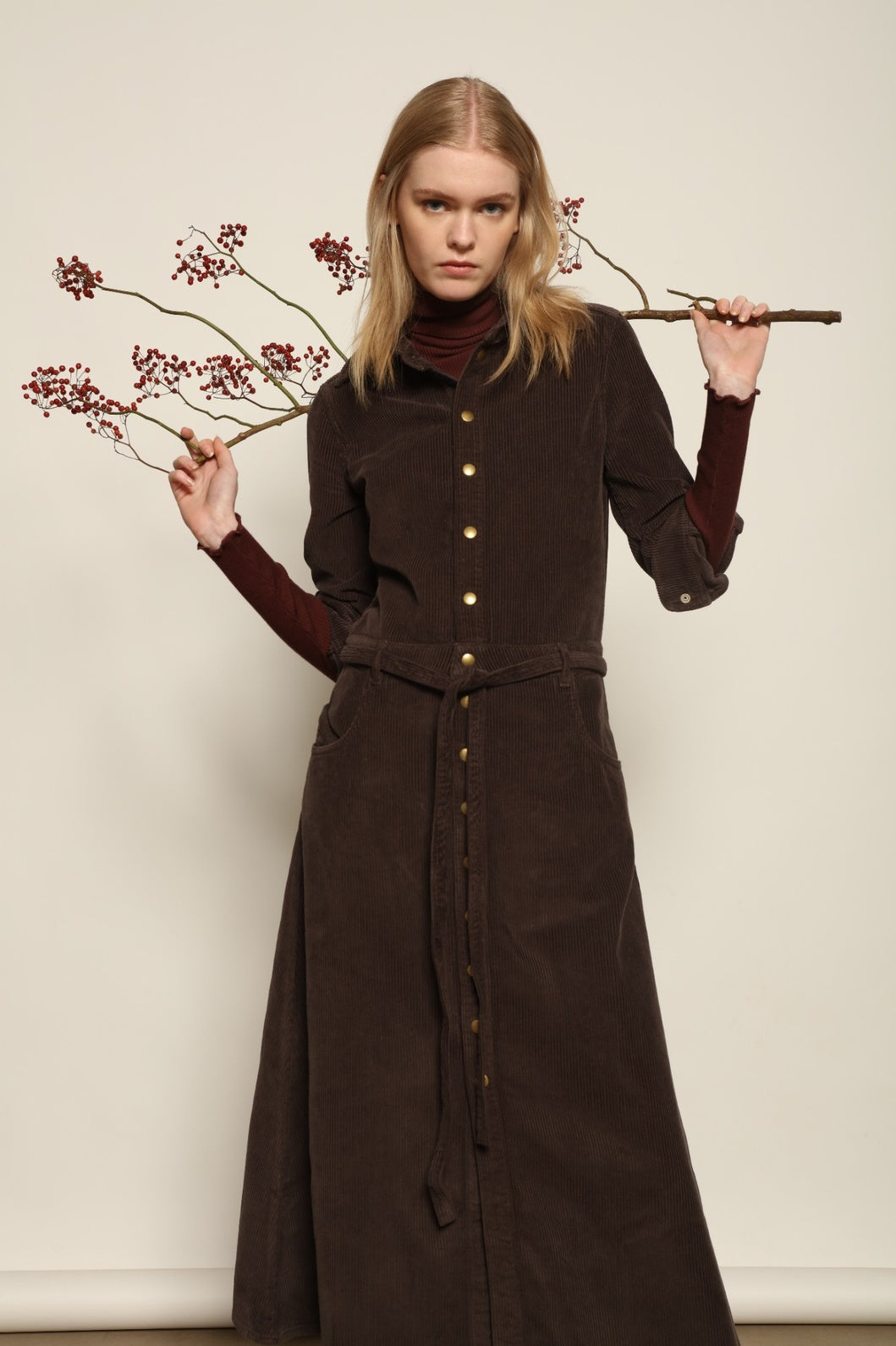 Model is wearing La Robe Trompe L’Oeil in Chocolate by Happy Haus, a corduroy cotton trompe-l’œil dress with removable belt, tulip-shaped pockets and brass snaps, curated in the House of Woven Stories selection.