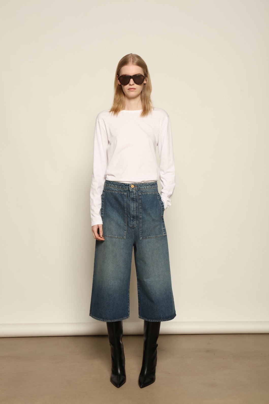 Model is wearing Le Bermuda 4 Poches by Happy Haus, organic denim mid-length bermuda shorts with four oversized patch pockets, curated in the House of Woven Stories selection.