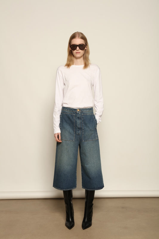 Model is wearing Le Bermuda 4 Poches by Happy Haus, organic denim mid-length bermuda shorts with four oversized patch pockets, curated in the House of Woven Stories selection.