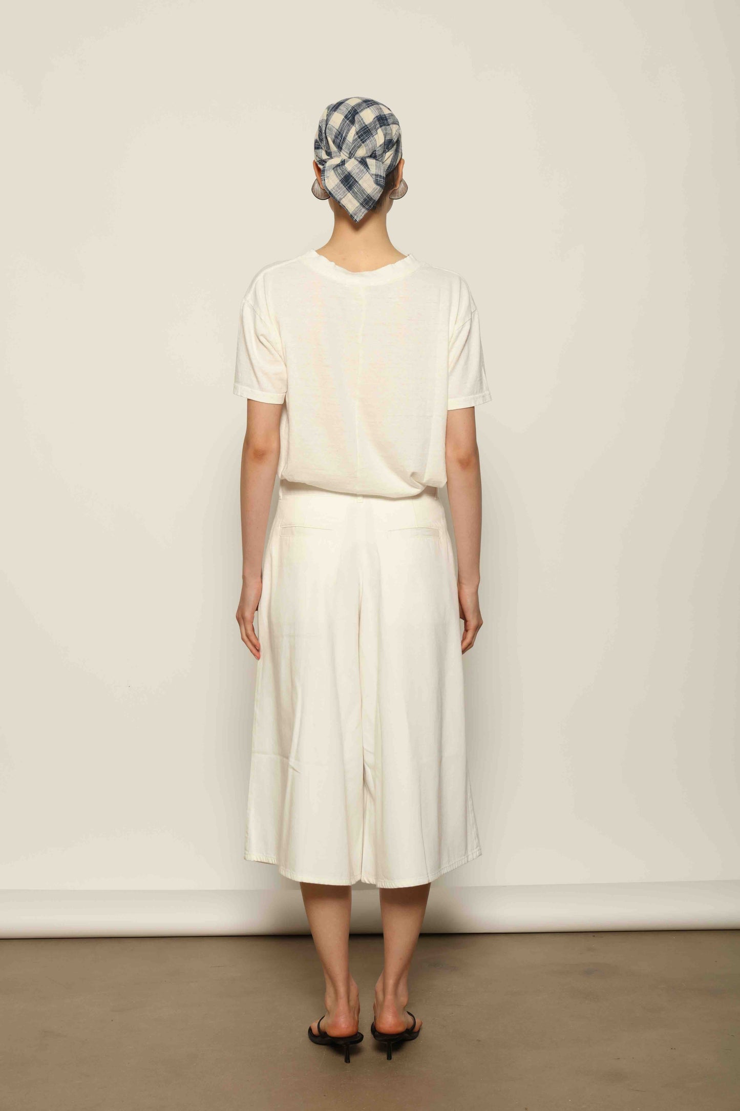Model wearing the La Jupe Culotte in Blanc Cassè by Happy Haus from the House of Nomad Stories collection, featuring premium Japanese denim, a high-waisted fit, wide-leg silhouette, and elegant ankle-length design.