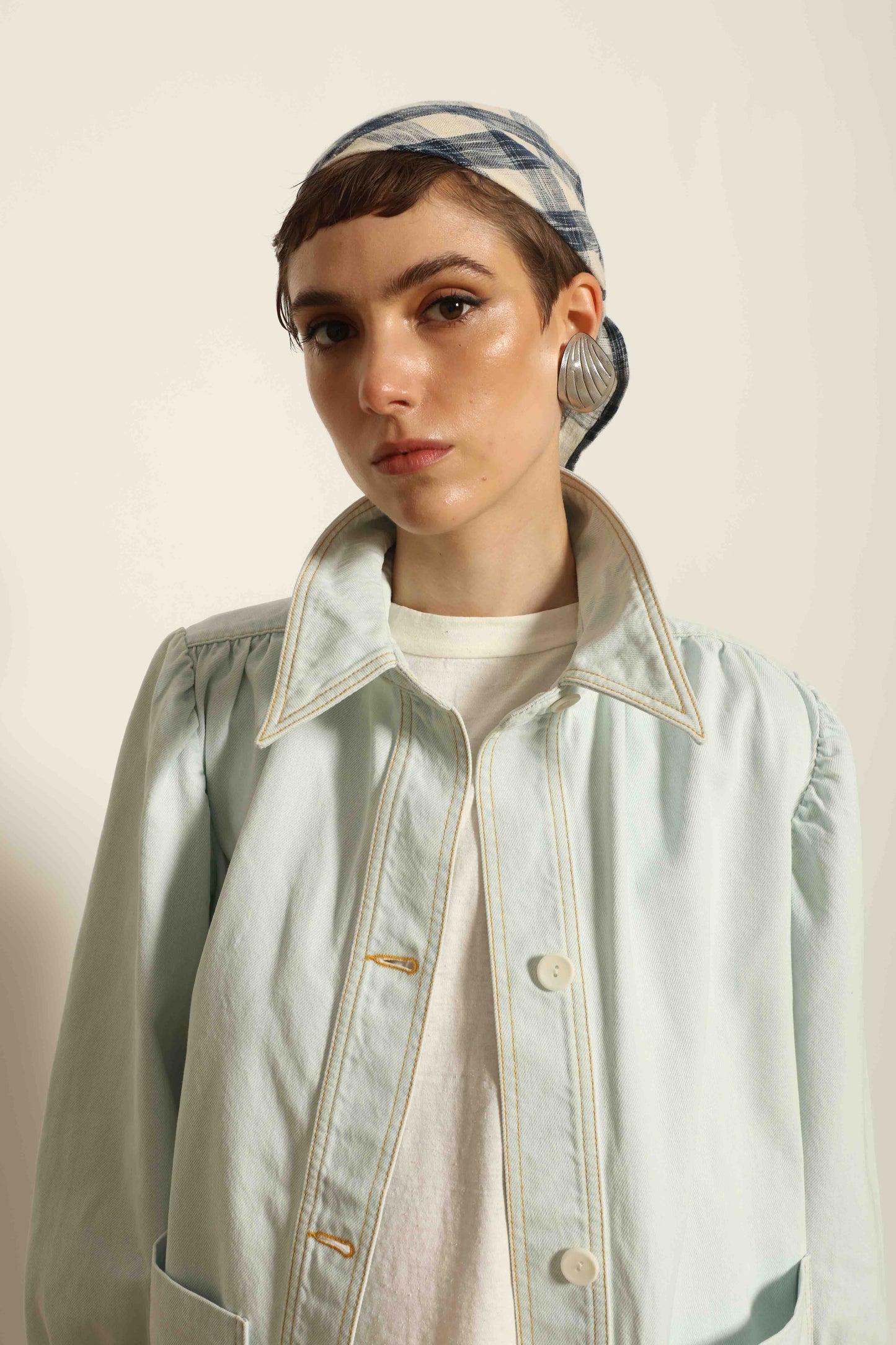 Model wearing the La Veste Peintre in Summer Blue by Happy Haus from the House of Nomad Stories collection, featuring a relaxed fit, light blue denim, patch pockets, wooden button closure, and workwear-inspired design.