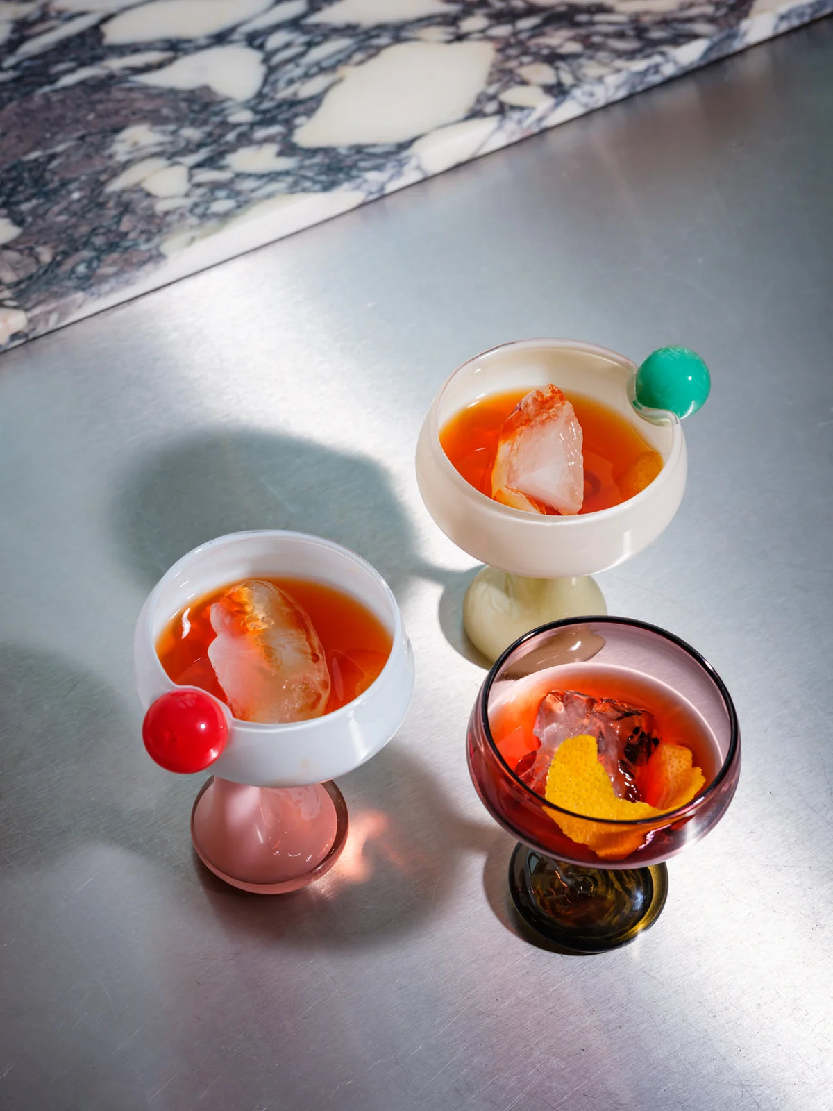 The Signature Glass with a Twist by Helle Mardahl Studio in Grapefruit, Blue Jelly and Milky Rose, handmade twisted glass drinking vessel from House of Nomad Stories.
