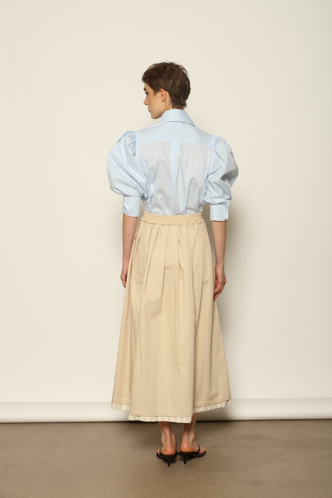 Model wearing the Karin Sky Blue Short Sleeves Blouse by House of Nomad Stories, featuring organic cotton fabric, sculptural balloon sleeves, structured silhouette, and a versatile neck tie detail.