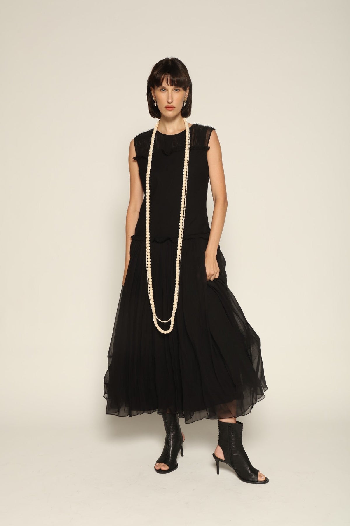 Model wearing a black silk Sera Dress by Abadia from the House of Nomad Stories collection, featuring a fitted bodice and fluid midi skirt with an elegant lightweight drape.