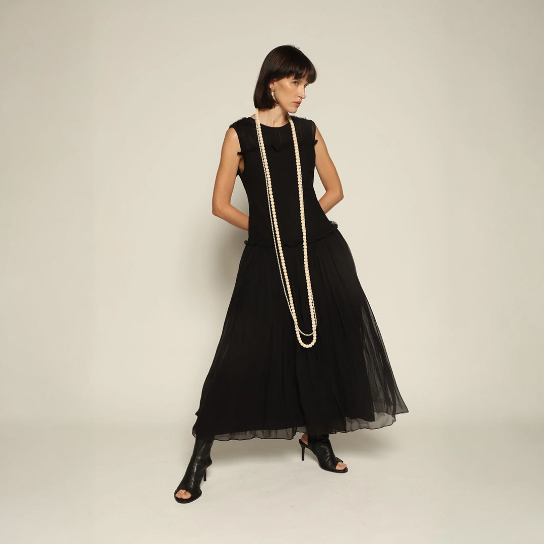 Model wearing a black silk Sera Dress by Abadia from the House of Nomad Stories collection, featuring a fitted bodice and fluid midi skirt with an elegant lightweight drape.