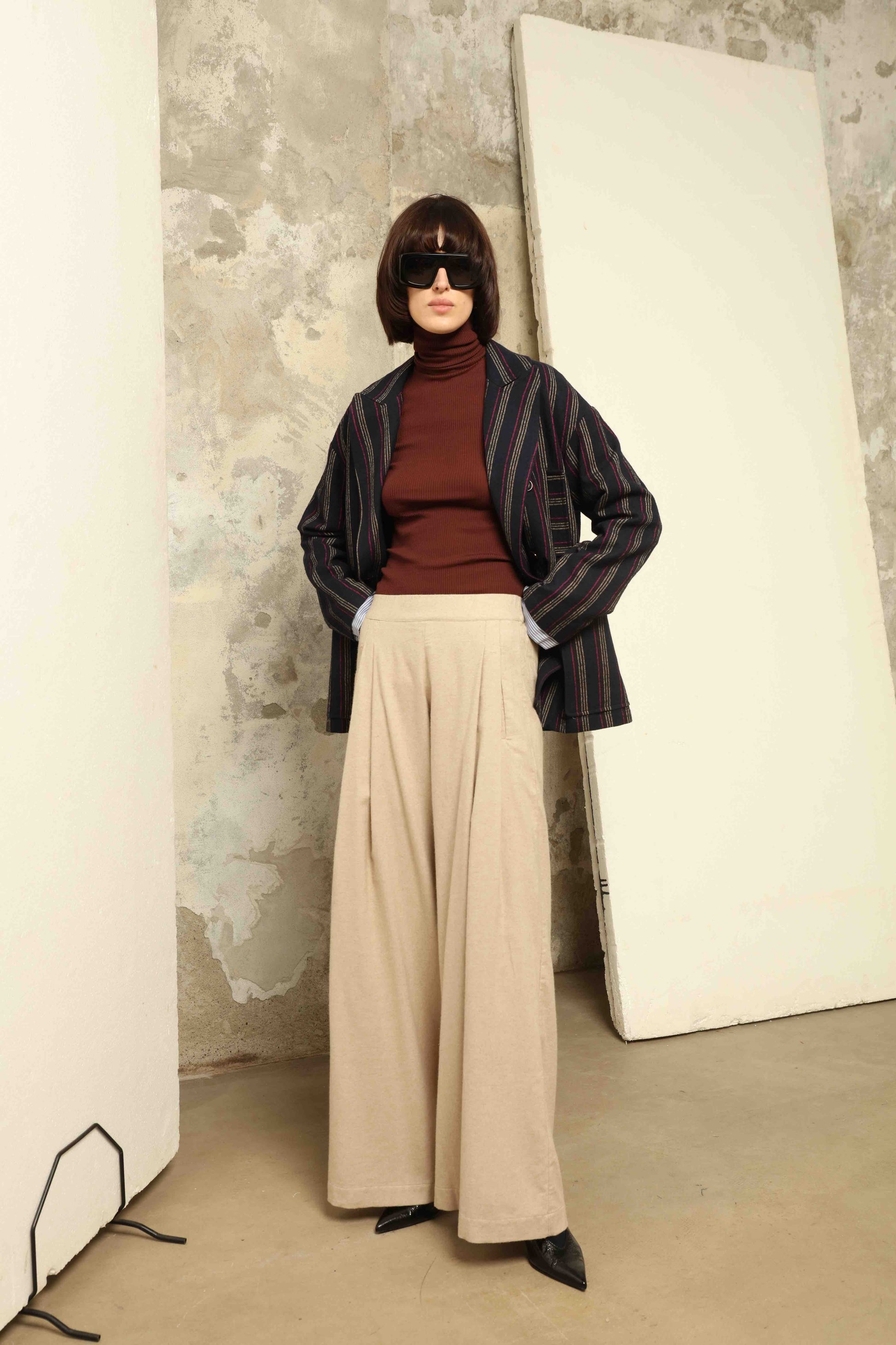 Model is wearing House of Woven Stories camel sweatpants, handmade in Italy with a relaxed fit and elasticated waist, crafted in sustainable luxury.