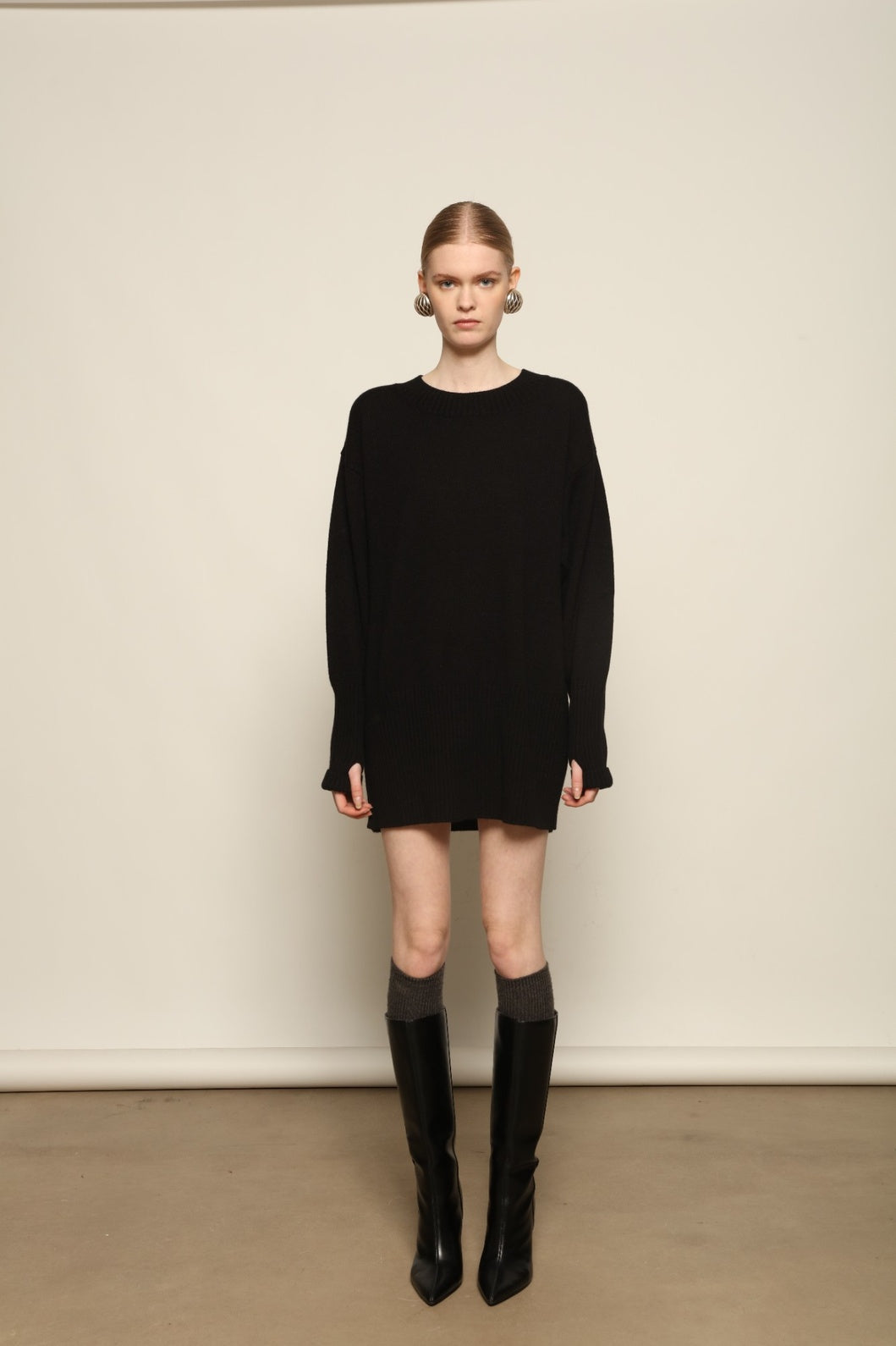 Model is wearing the Black Noemi Round Neck Long Sweater by House of Woven Stories, a pure ethically sourced cashmere knit in deep black with long silhouette, round neckline and ribbed edges.