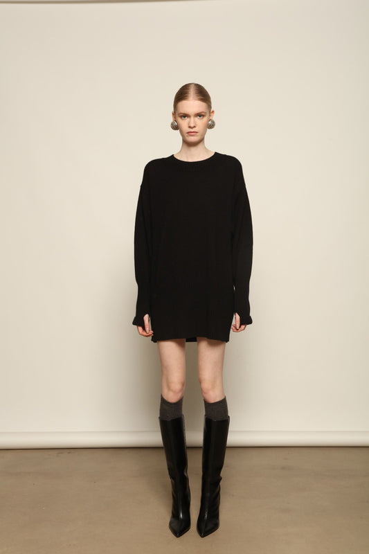 Model is wearing the Black Noemi Round Neck Long Sweater by House of Woven Stories, a pure ethically sourced cashmere knit in deep black with long silhouette, round neckline and ribbed edges.