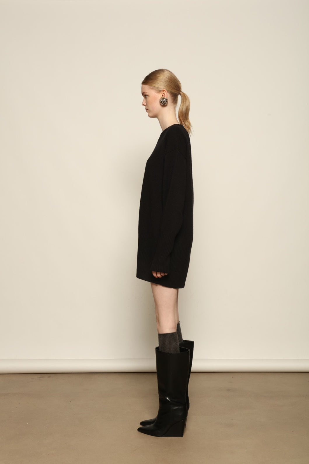 Model is wearing the Black Noemi Round Neck Long Sweater by House of Woven Stories, a pure ethically sourced cashmere knit in deep black with long silhouette, round neckline and ribbed edges.