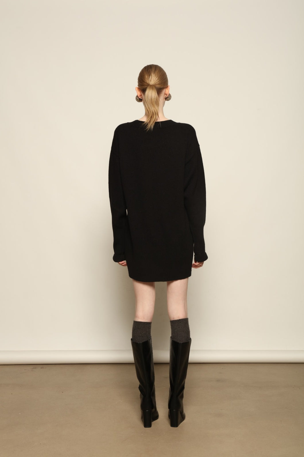 Model is wearing the Black Noemi Round Neck Long Sweater by House of Woven Stories, a pure ethically sourced cashmere knit in deep black with long silhouette, round neckline and ribbed edges.