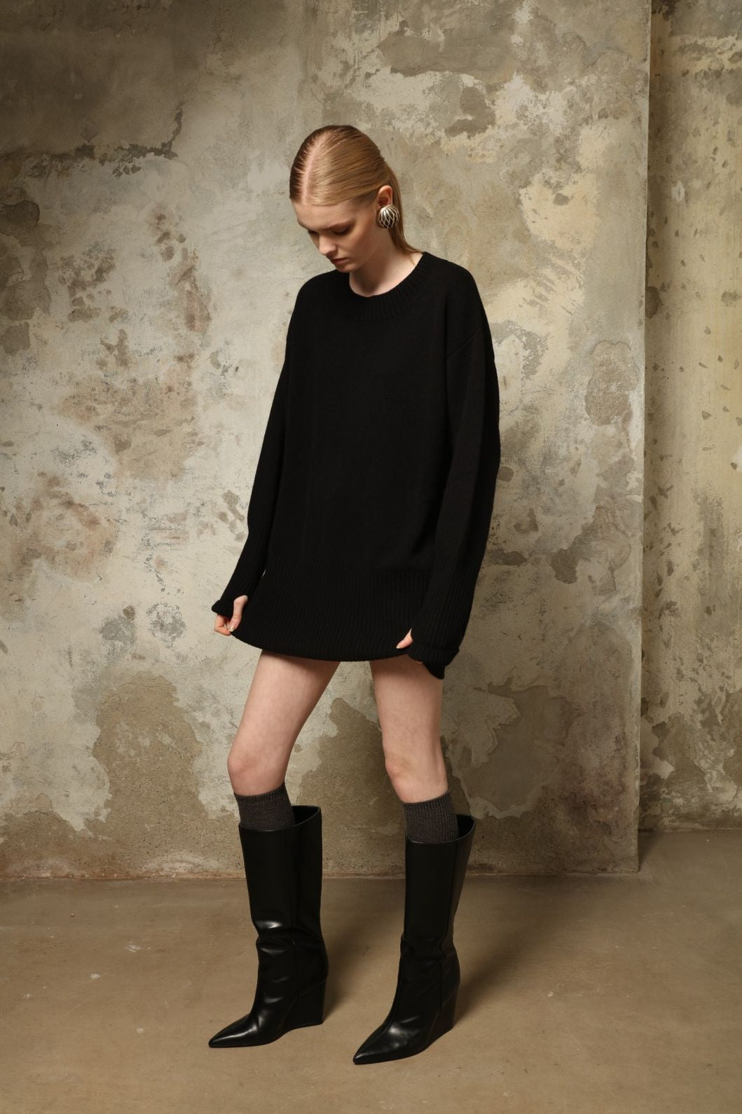 Model is wearing the Black Noemi Round Neck Long Sweater by House of Woven Stories, a pure ethically sourced cashmere knit in deep black with long silhouette, round neckline and ribbed edges.