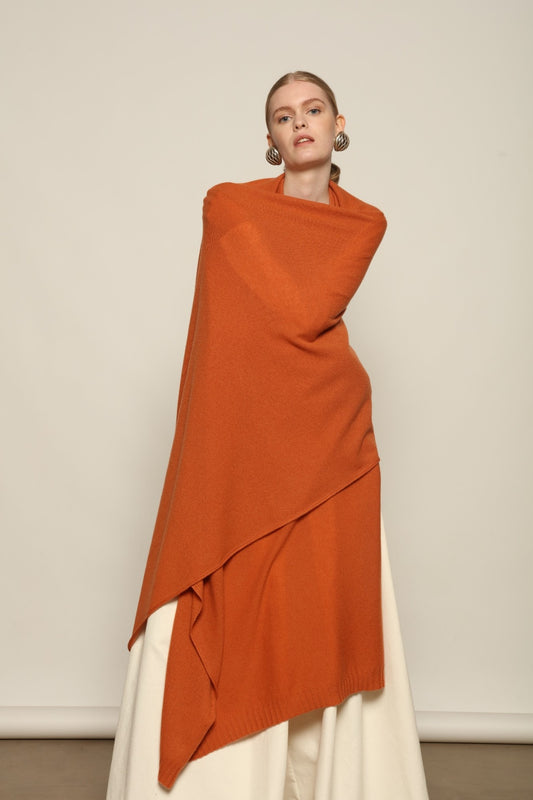 Model is wearing the Brick Leni Scarf by House of Woven Stories, a pure ethically sourced cashmere scarf with refined texture, enduring softness and fluid drape in a warm brick tone.