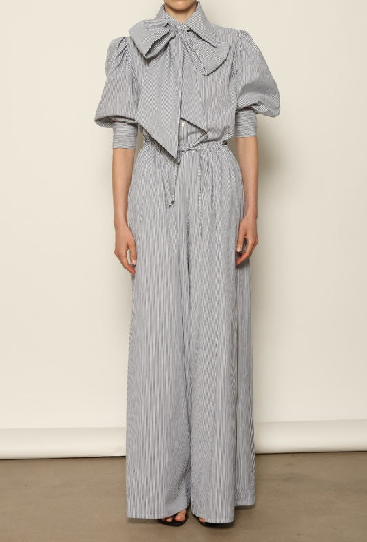 Model wearing the Brigitta White Navy Striped Trousers by House of Woven Stories, featuring 100% organic cotton fabric, high-rise waist, wide-leg silhouette, and classic white and navy stripes.