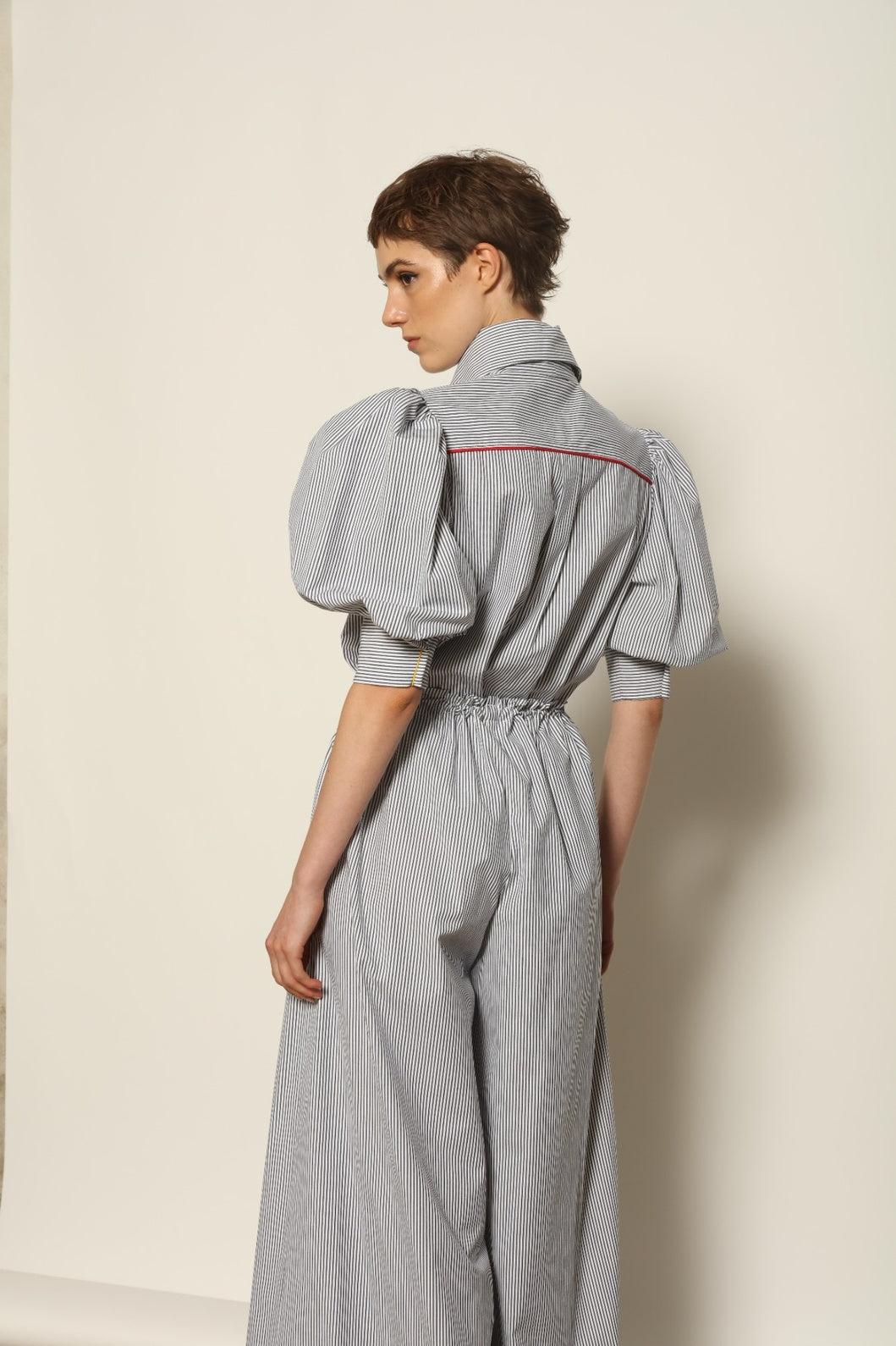 Model wearing the Brigitta White Navy Striped Trousers by House of Woven Stories, featuring 100% organic cotton fabric, high-rise waist, wide-leg silhouette, and classic white and navy stripes.