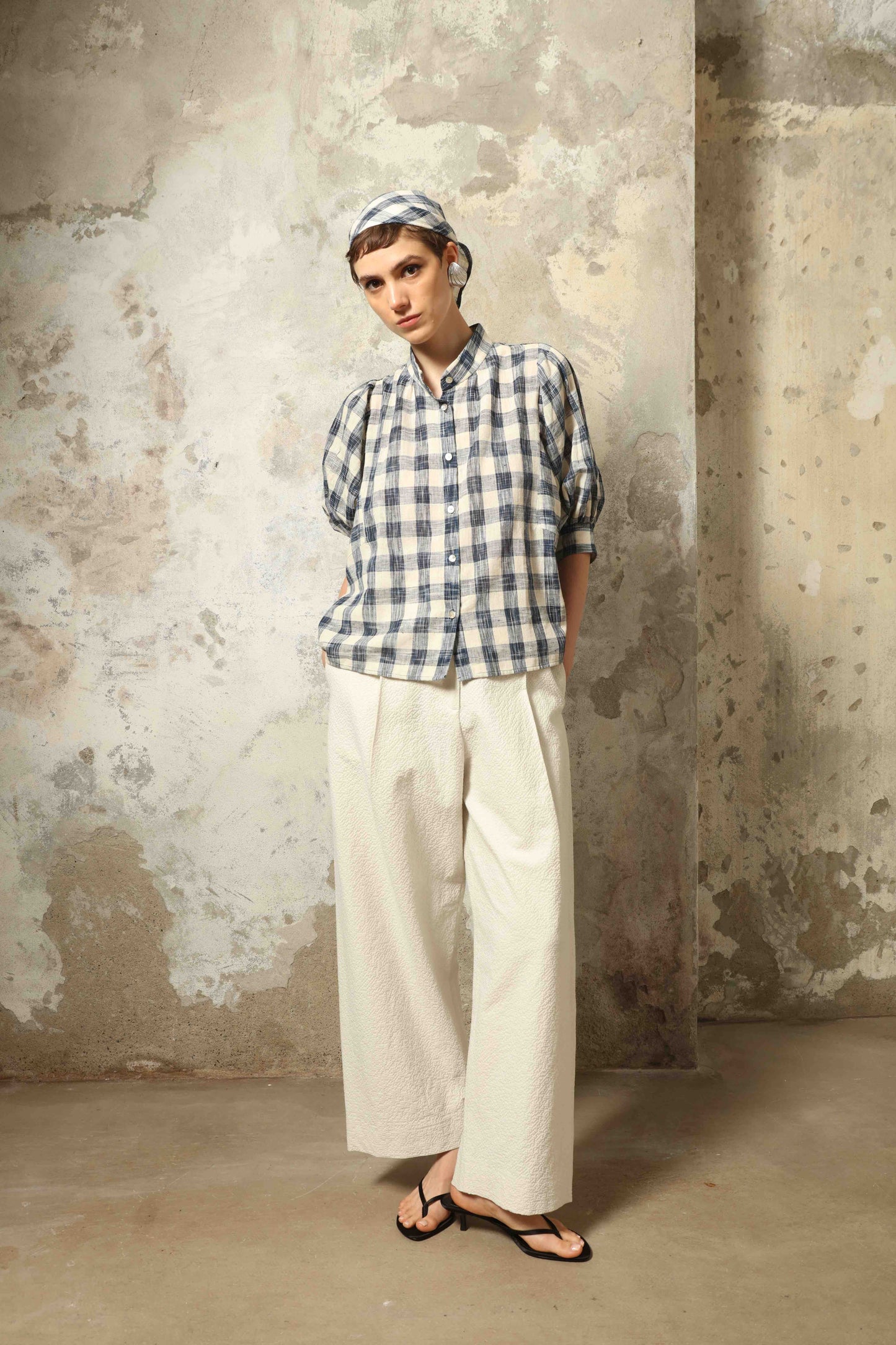 Model wearing the White Brigitta Organic Cotton Trousers by House of Woven Stories, featuring a relaxed fit, lightweight organic cotton fabric, and a timeless minimalist silhouette made in Italy.
