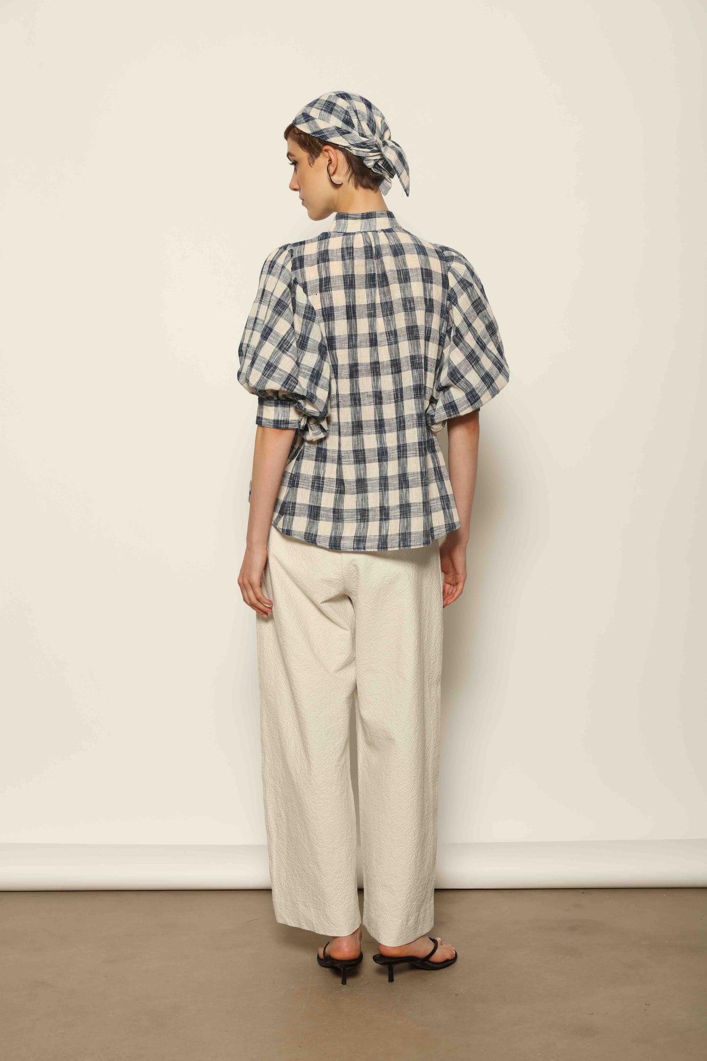 Model wearing the White Brigitta Organic Cotton Trousers by House of Woven Stories, featuring a relaxed fit, lightweight organic cotton fabric, and a timeless minimalist silhouette made in Italy.
