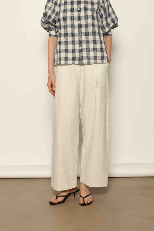 Model wearing the White Brigitta Organic Cotton Trousers by House of Woven Stories, featuring a relaxed fit, lightweight organic cotton fabric, and a timeless minimalist silhouette made in Italy.
