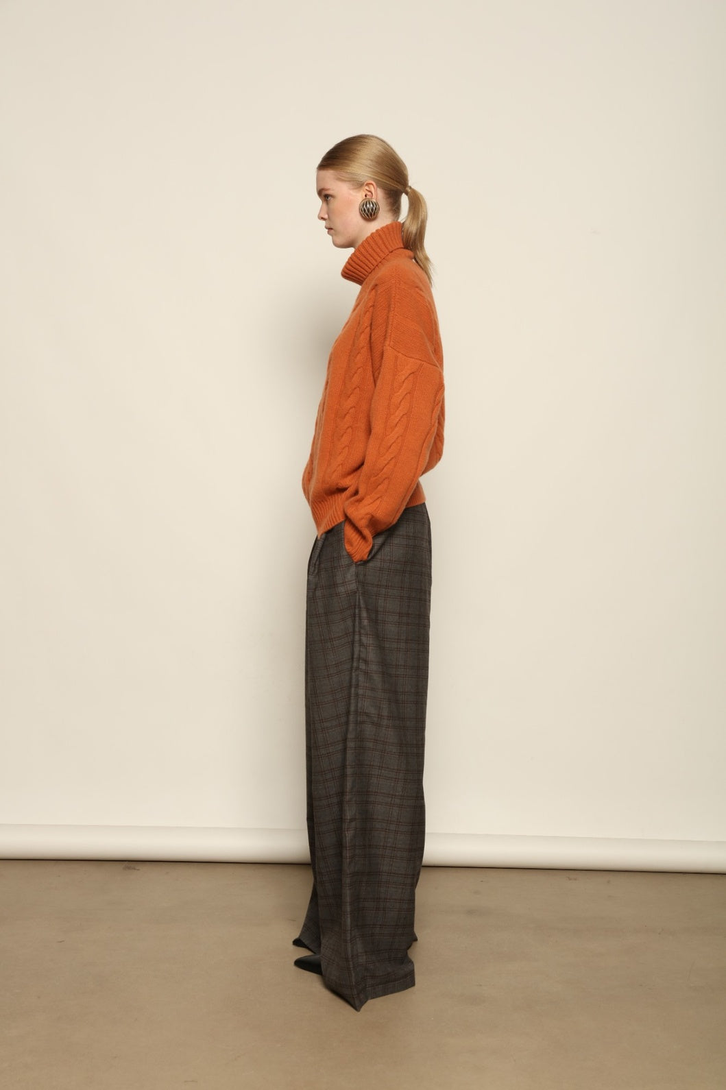 Model is wearing the Brown Check Parigi Pants by House of Woven Stories, relaxed straight-leg Merino wool trousers with a soft brown check pattern, handcrafted in Italy.