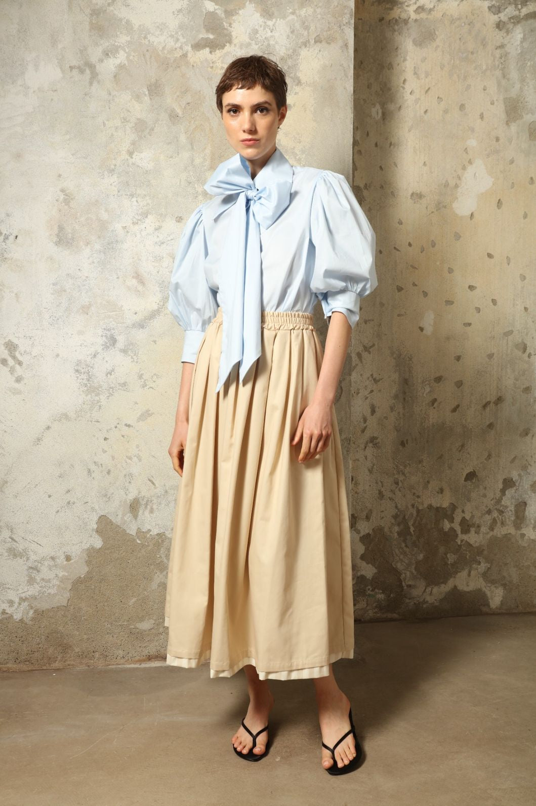 Model wearing the Seoul Camel Skirt by House of Woven Stories, featuring a structured camel-toned fabric, high-waisted fit, and a clean tailored silhouette with defined architectural lines.