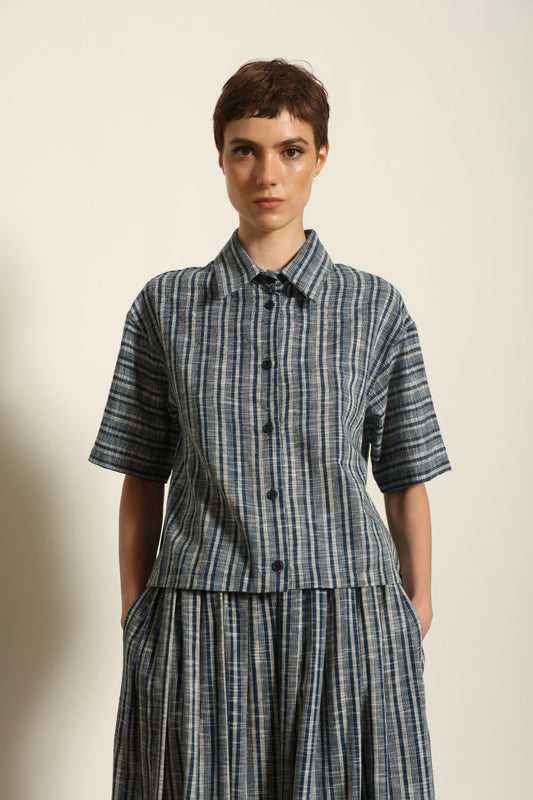 Model wearing the Emily Blue Striped Ikat Shirt by House of Woven Stories, crafted from 100% hand-loomed Kala cotton with indigo stripes, artisanal ikat pattern, and a relaxed cropped silhouette.