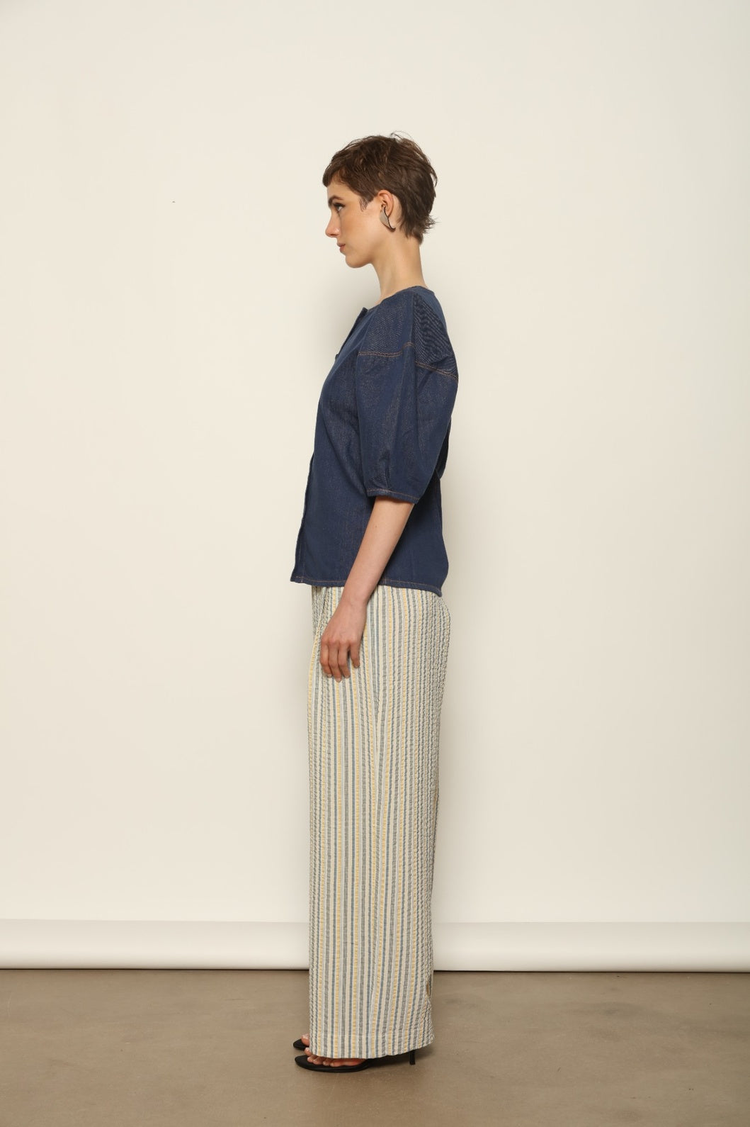 Model wearing the Gabriella Yellow China Blue Seersucker Silk Trousers by House of Woven Stories, featuring silk seersucker fabric, yellow and china blue color palette, textured surface, and fluid elegant silhouette.