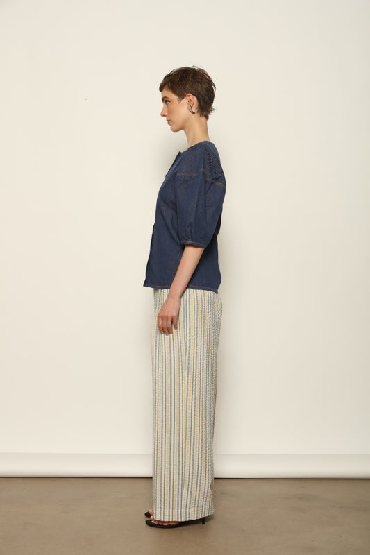 Model wearing the Gabriella Yellow China Blue Seersucker Silk Trousers by House of Woven Stories, featuring silk seersucker fabric, yellow and china blue color palette, textured surface, and fluid elegant silhouette.