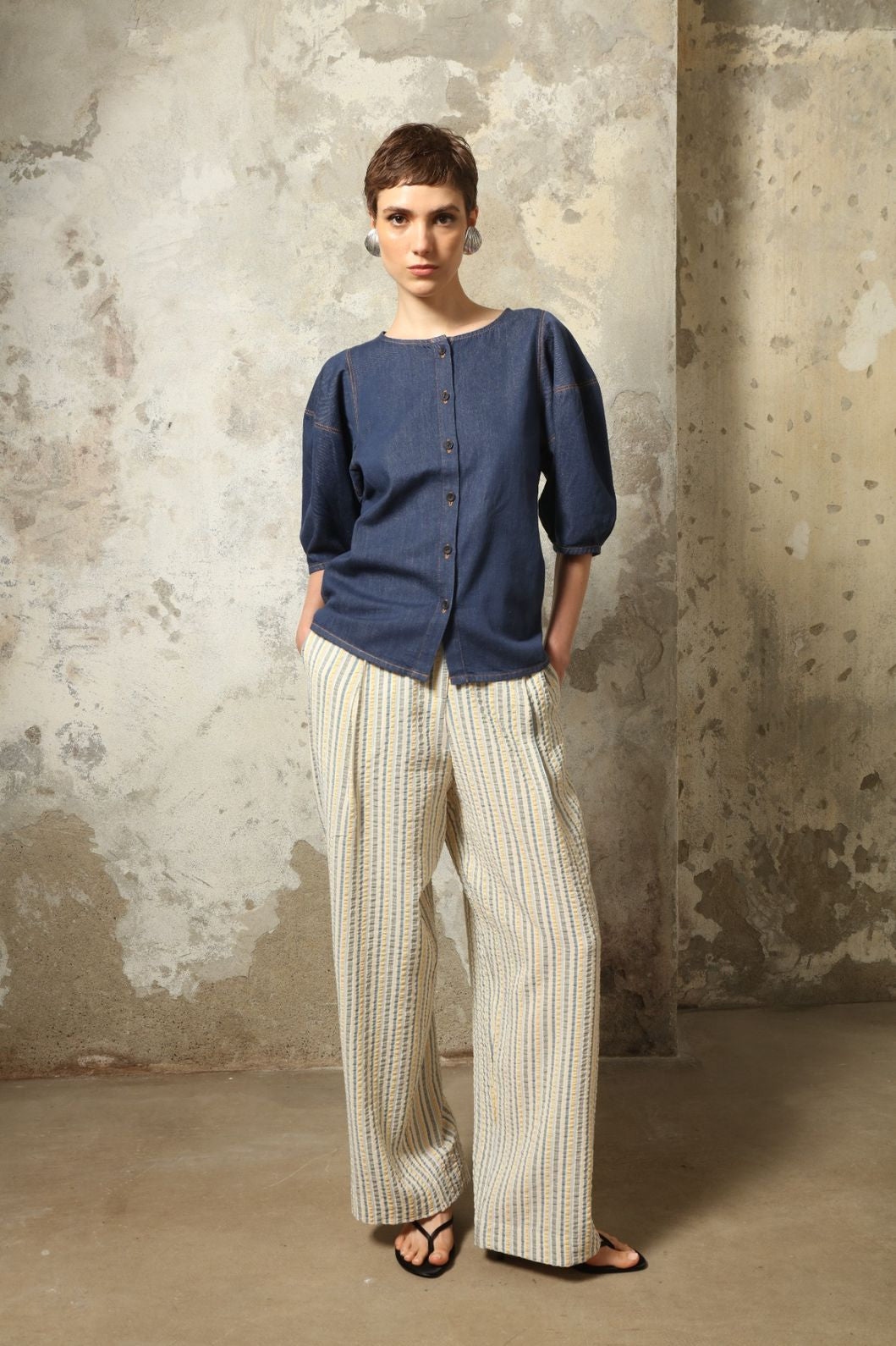 Model wearing the Gabriella Yellow China Blue Seersucker Silk Trousers by House of Woven Stories, featuring silk seersucker fabric, yellow and china blue color palette, textured surface, and fluid elegant silhouette.