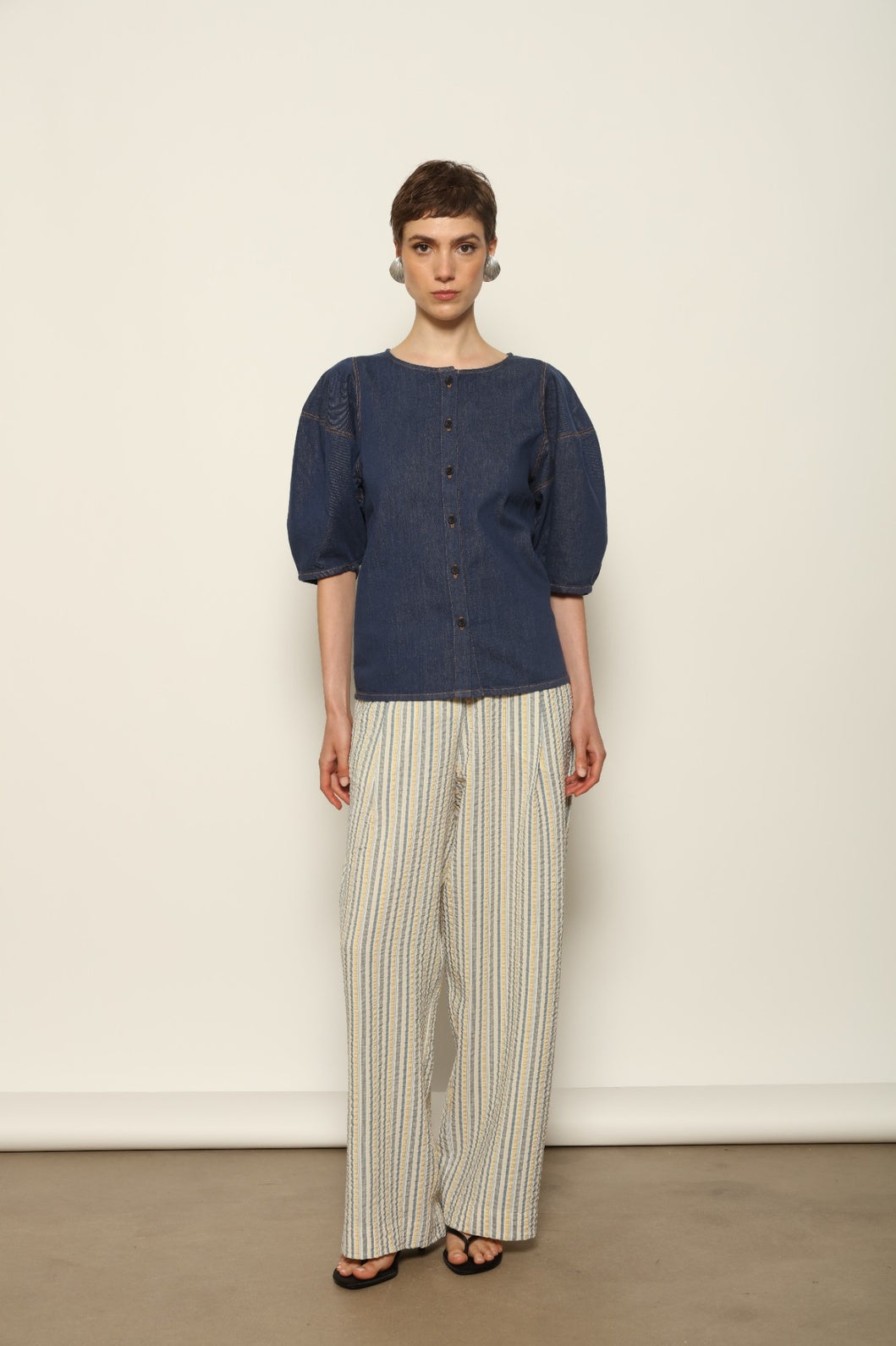 Model wearing the Gabriella Yellow China Blue Seersucker Silk Trousers by House of Woven Stories, featuring silk seersucker fabric, yellow and china blue color palette, textured surface, and fluid elegant silhouette.
