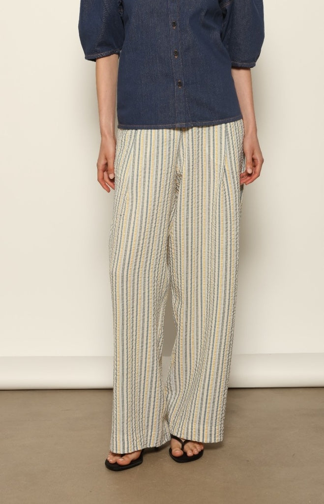 Model wearing the Gabriella Yellow China Blue Seersucker Silk Trousers by House of Woven Stories, featuring silk seersucker fabric, yellow and china blue color palette, textured surface, and fluid elegant silhouette.