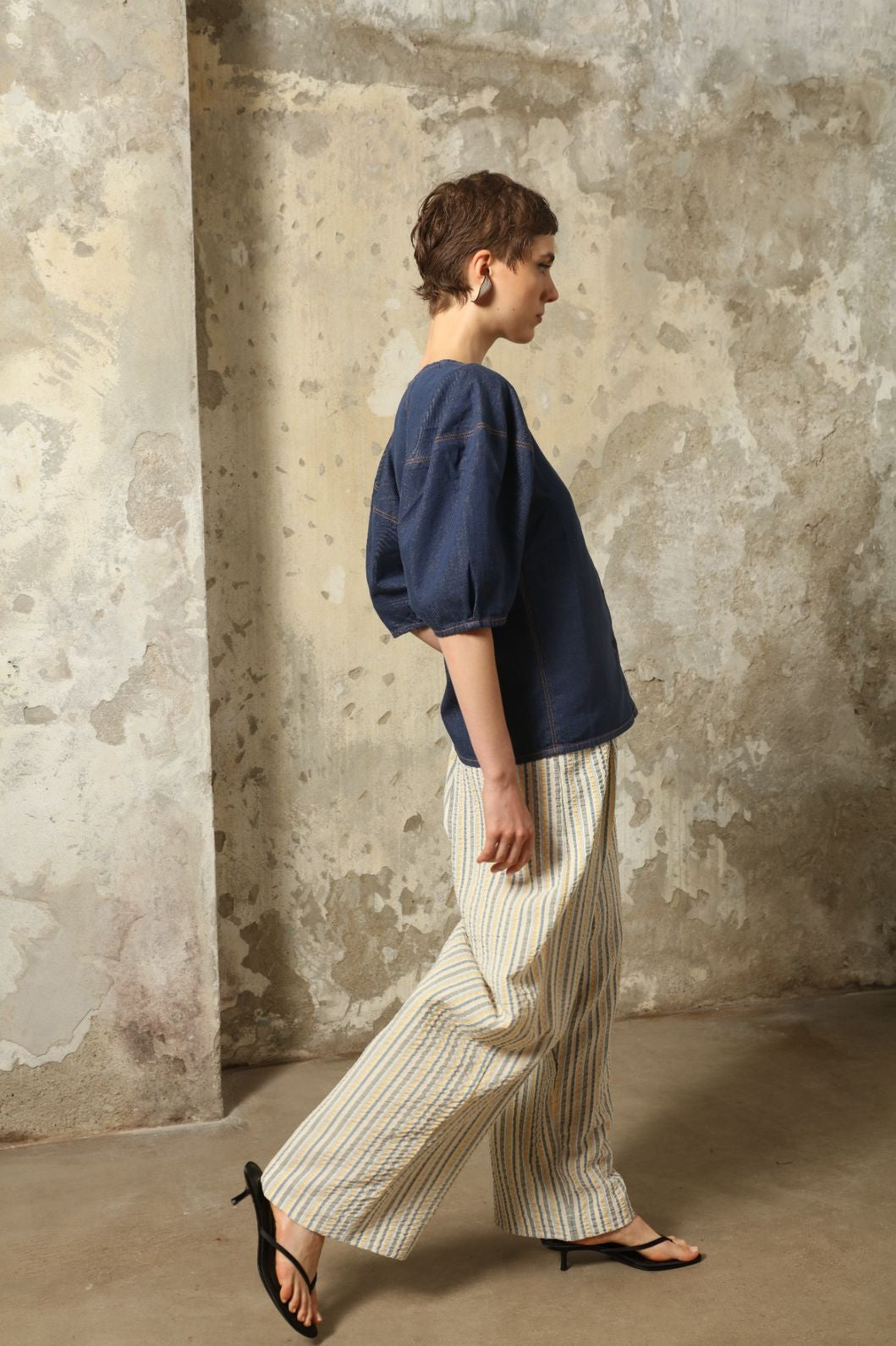Model wearing the Gabriella Yellow China Blue Seersucker Silk Trousers by House of Woven Stories, featuring silk seersucker fabric, yellow and china blue color palette, textured surface, and fluid elegant silhouette.