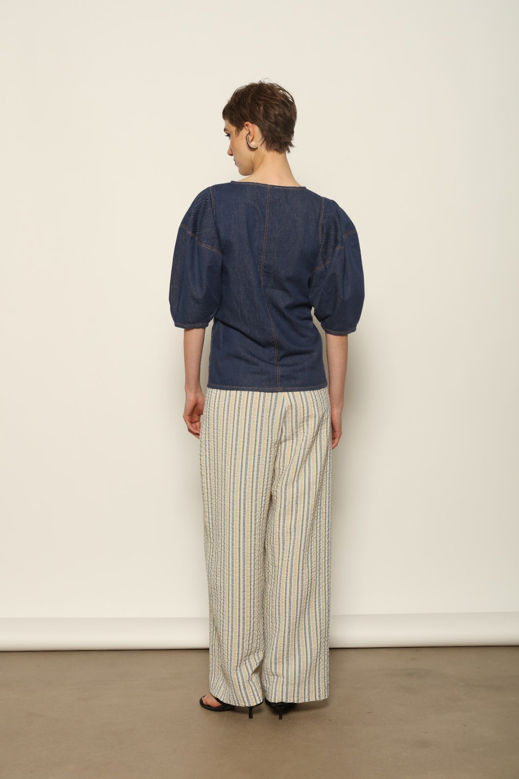 Model wearing the Gabriella Yellow China Blue Seersucker Silk Trousers by House of Woven Stories, featuring silk seersucker fabric, yellow and china blue color palette, textured surface, and fluid elegant silhouette.