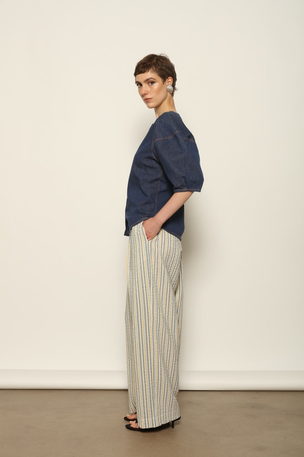 Model wearing the Gabriella Yellow China Blue Seersucker Silk Trousers by House of Woven Stories, featuring silk seersucker fabric, yellow and china blue color palette, textured surface, and fluid elegant silhouette.
