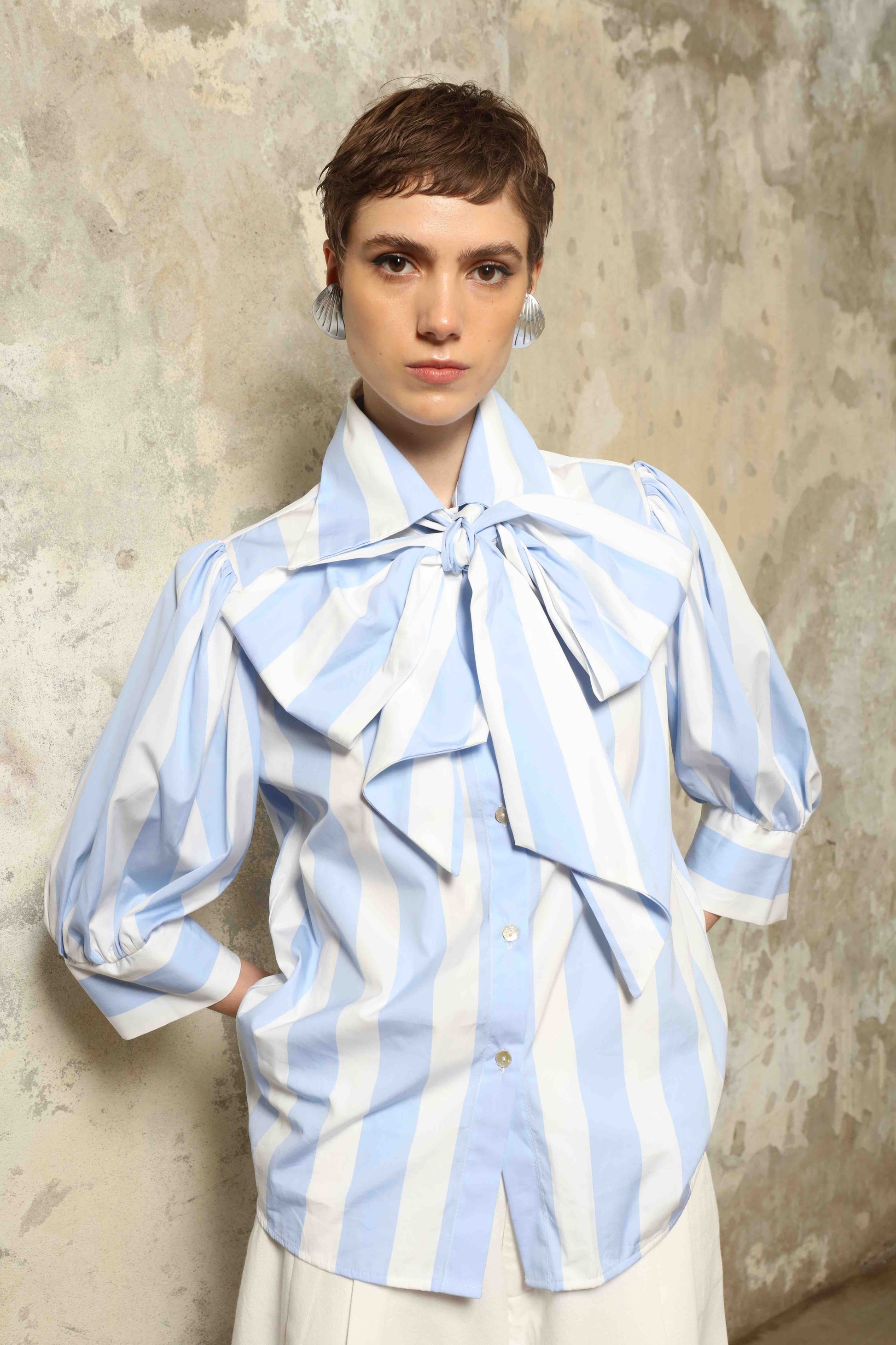 Model wearing the Karin Blue and White Macro Striped Blouse by House of Woven Stories, featuring bold macro stripes, relaxed fit silhouette, and lightweight 100% organic cotton fabric made in Italy.