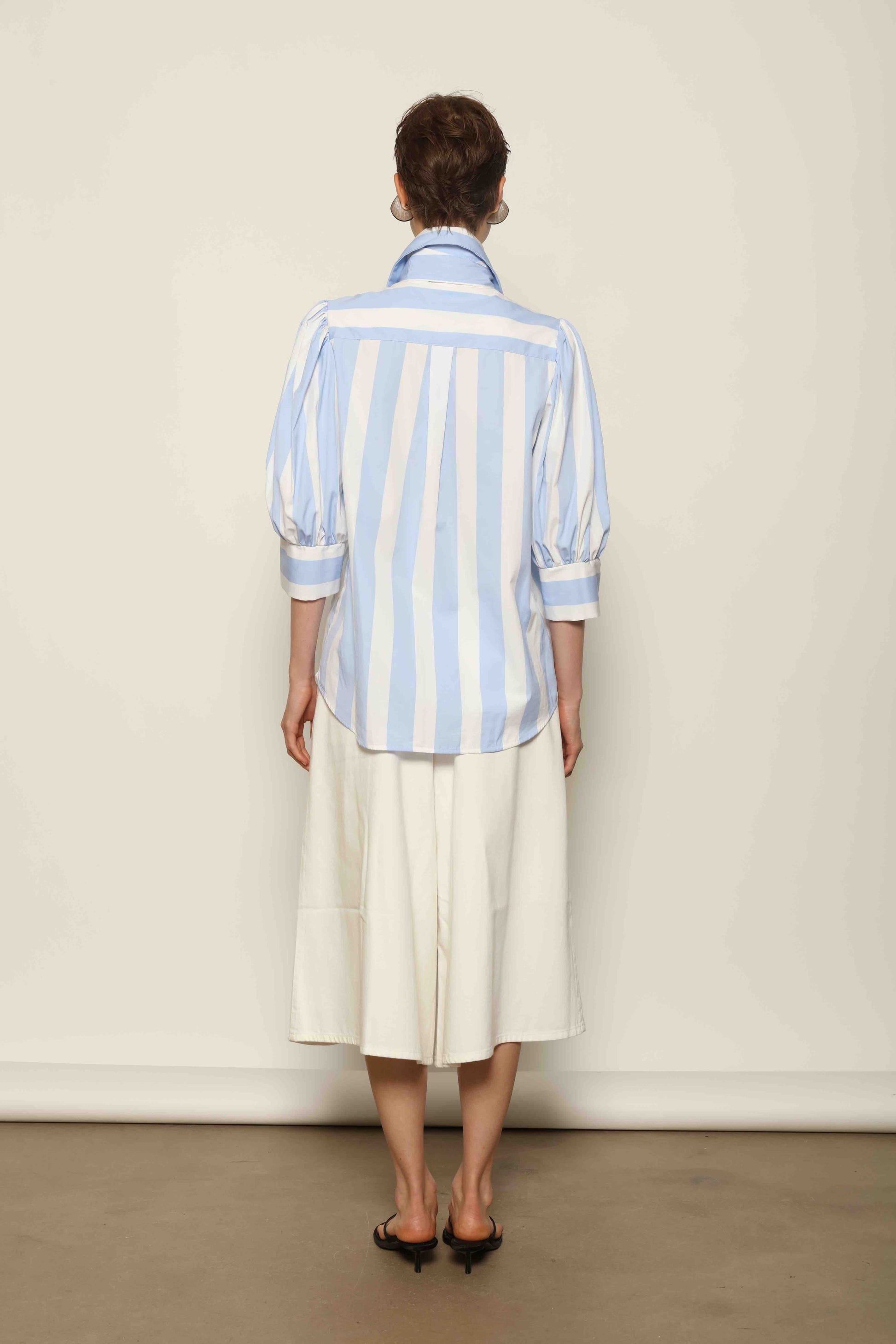 Model wearing the Karin Blue and White Macro Striped Blouse by House of Woven Stories, featuring bold macro stripes, relaxed fit silhouette, and lightweight 100% organic cotton fabric made in Italy.