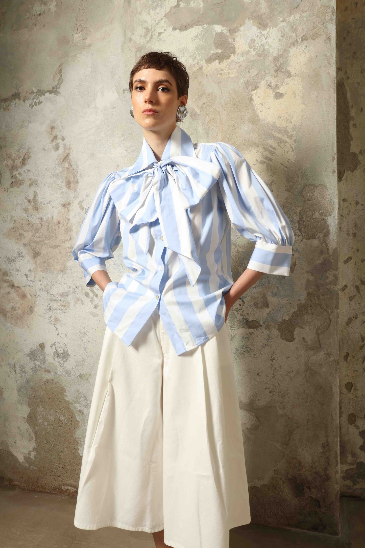 Model wearing the Karin Blue and White Macro Striped Blouse by House of Woven Stories, featuring bold macro stripes, relaxed fit silhouette, and lightweight 100% organic cotton fabric made in Italy.